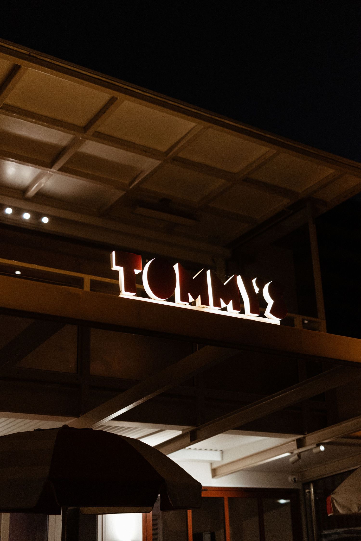 Illuminated 'Luma's' signage mounted on a dark wooden ceiling with spotlights.