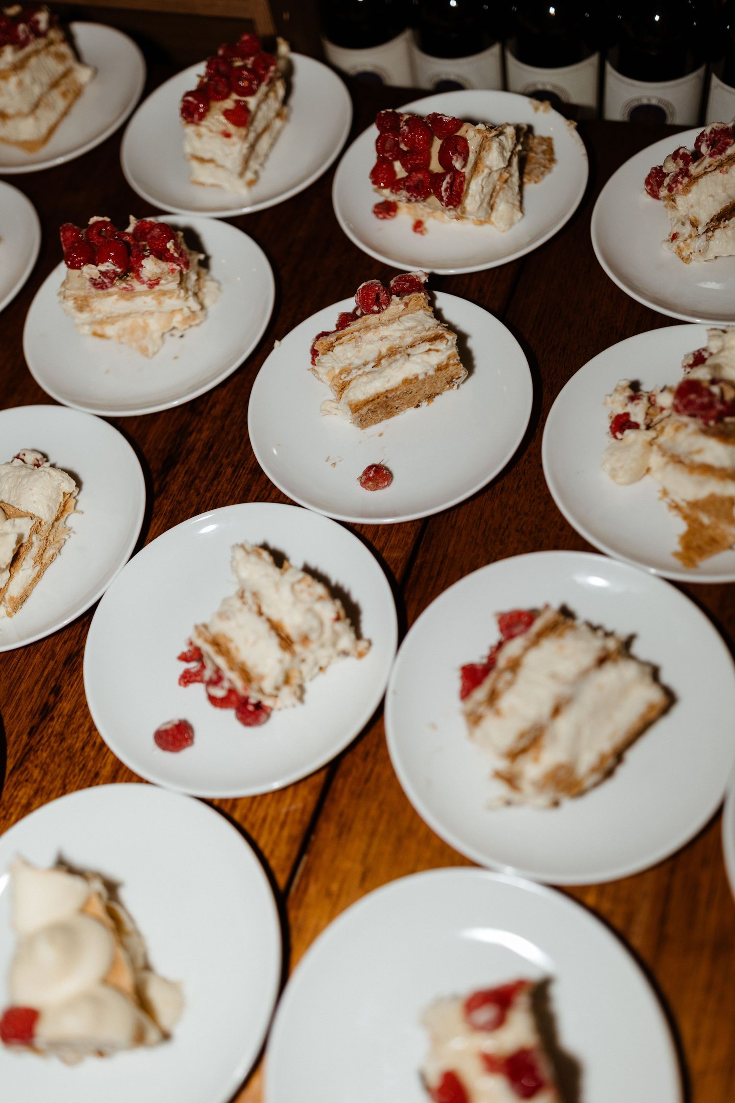 Slices of layered white cake topped with red berries arranged on white plates.