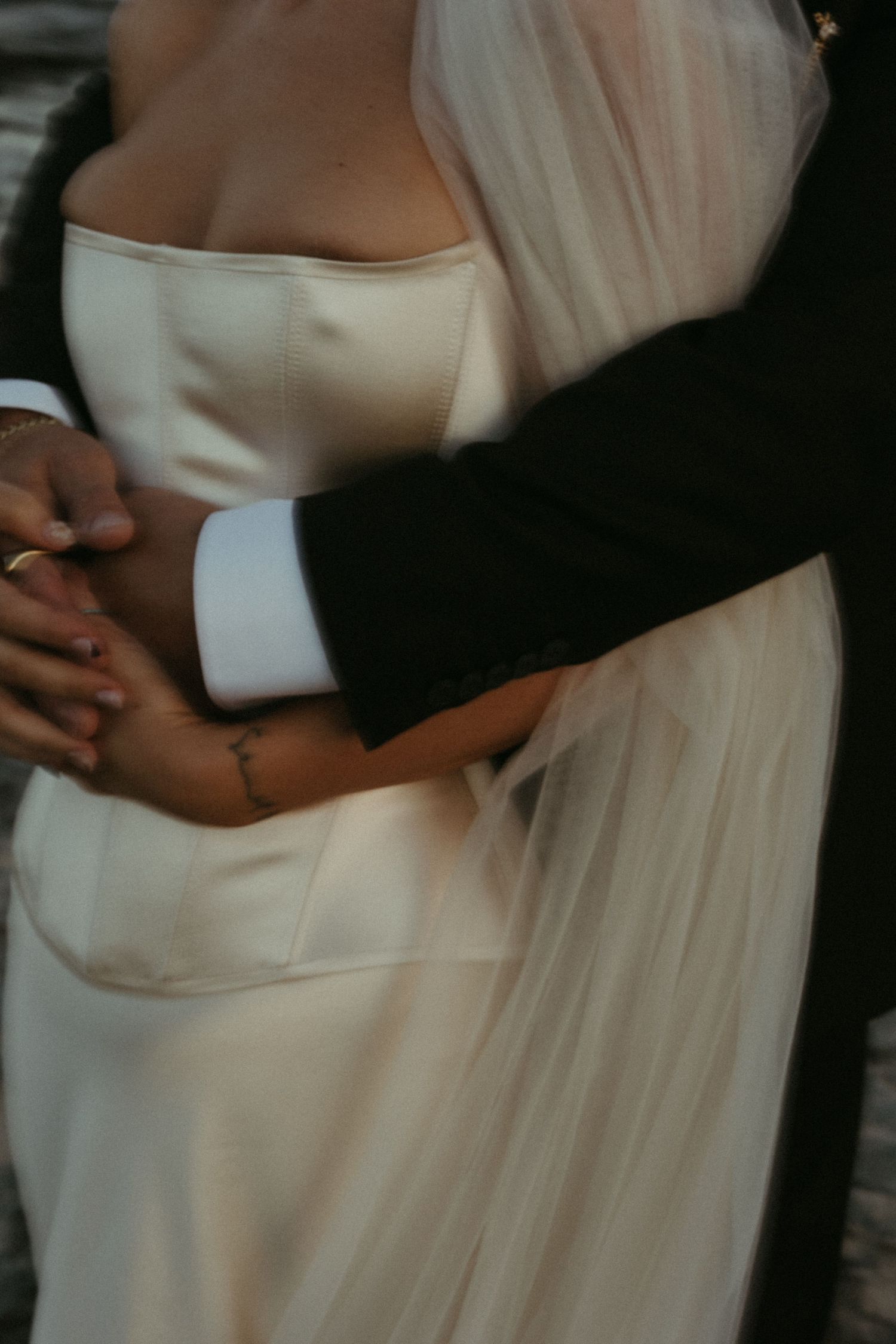Intimate portrait of newlyweds embracing, with bride in strapless white dress and flowing veil.