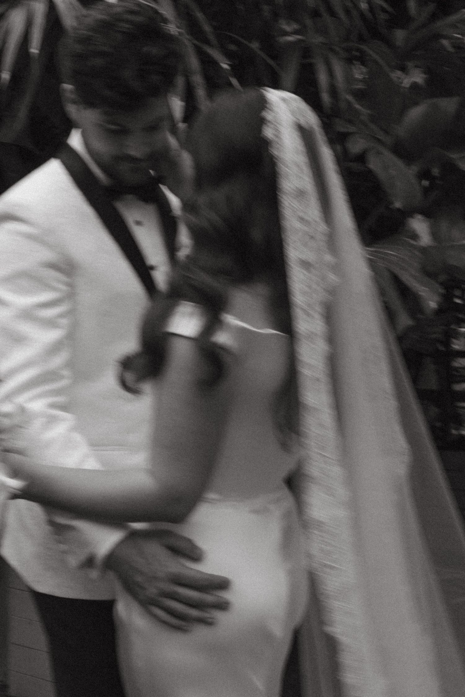 Wedding guests dance close together in formal attire at an elegant black and white reception celebration.