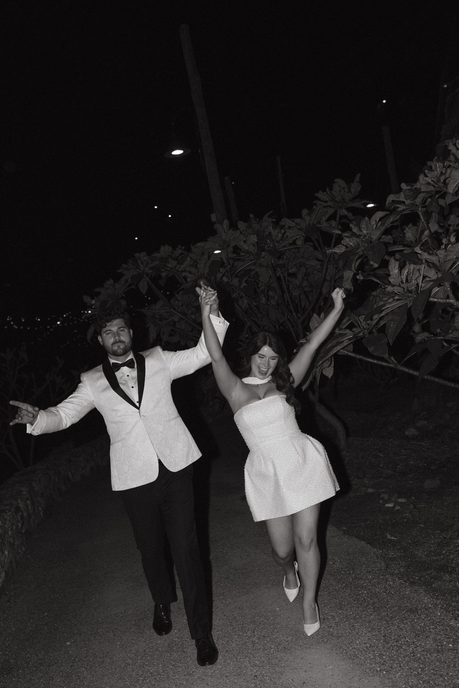 A joyful couple celebrates while walking outdoors at night.