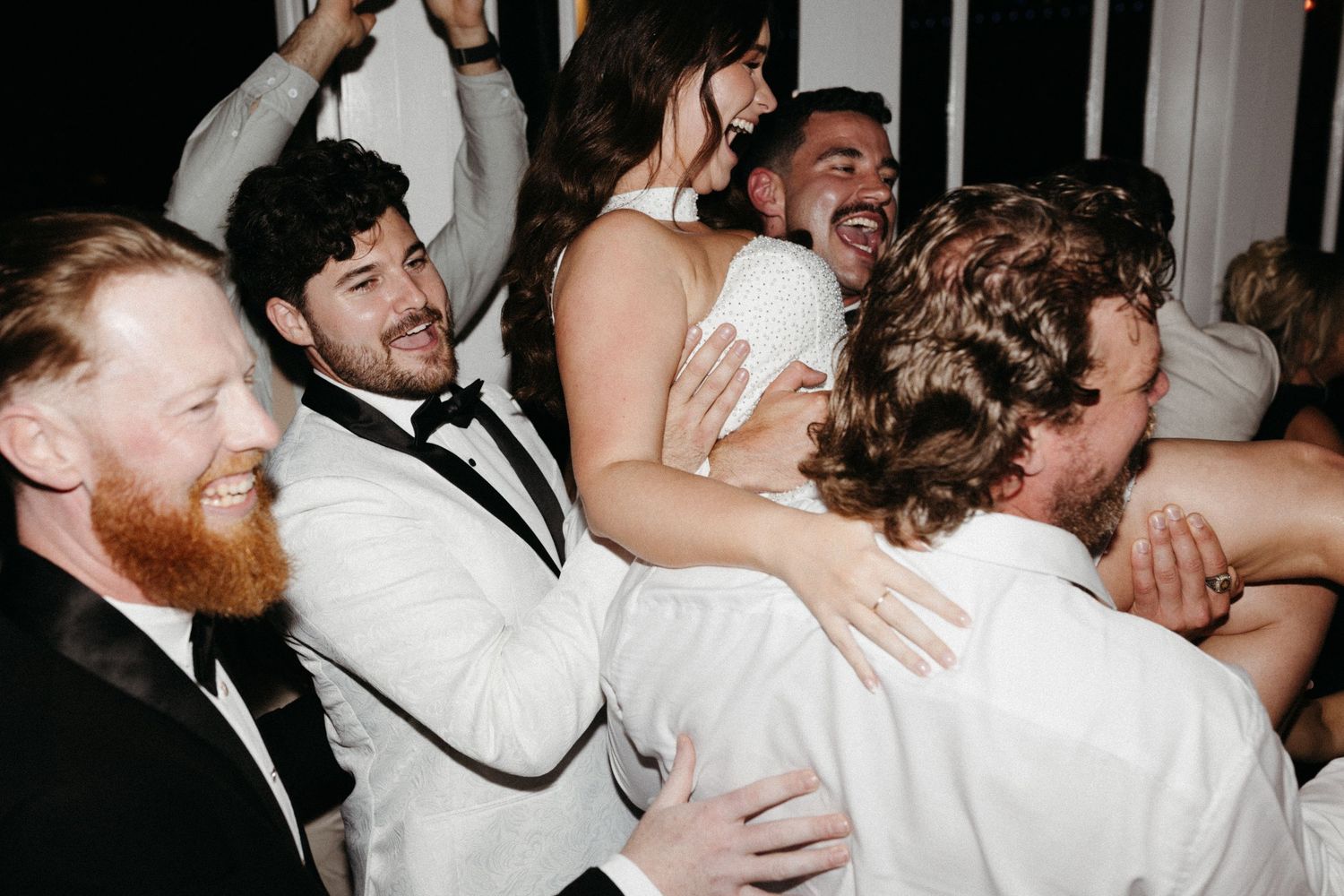 Wedding guests share joyful hugs and embraces during an emotional reception celebration.