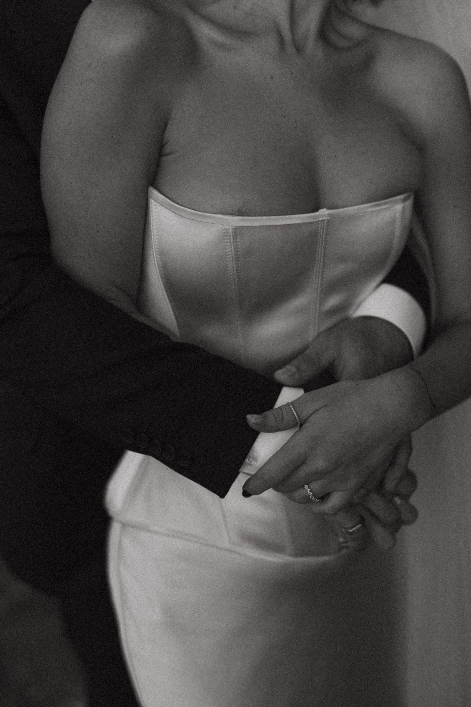 Close-up black and white photo of a bride in a structured white corset dress showing elegant craftsmanship.