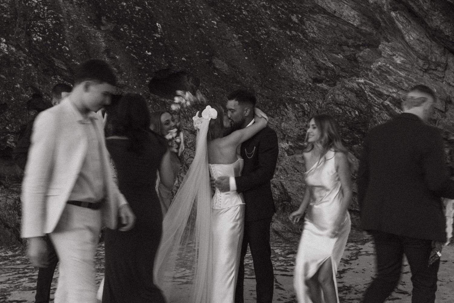 A candid black and white photo shows people in white outfits gathered outdoors during what appears to be a special occasion.