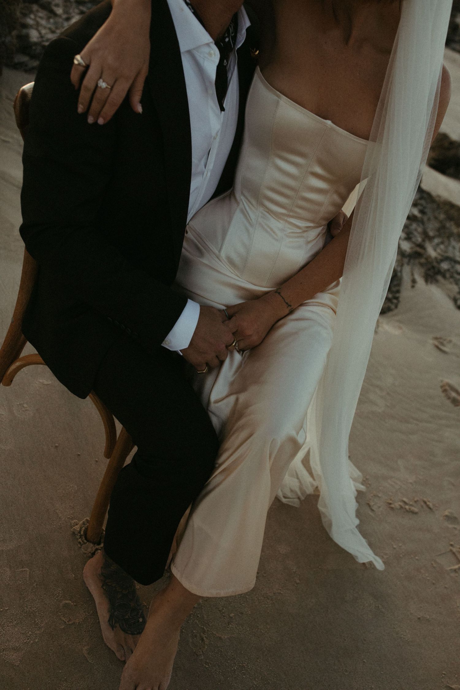 Close-up details of a bride's white wedding dress and couple's intimate poses on a beach.