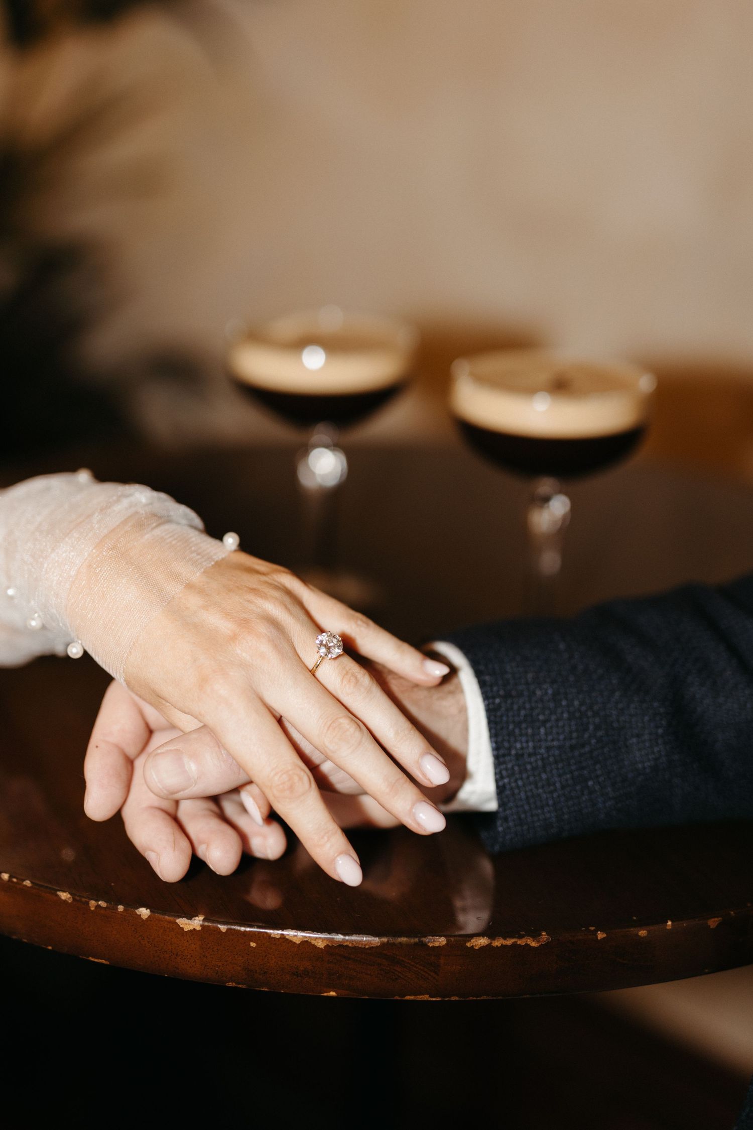 Close-up sequence showing hands with a ring on a dark table in warm ambient lighting creating an intimate atmosphere.
