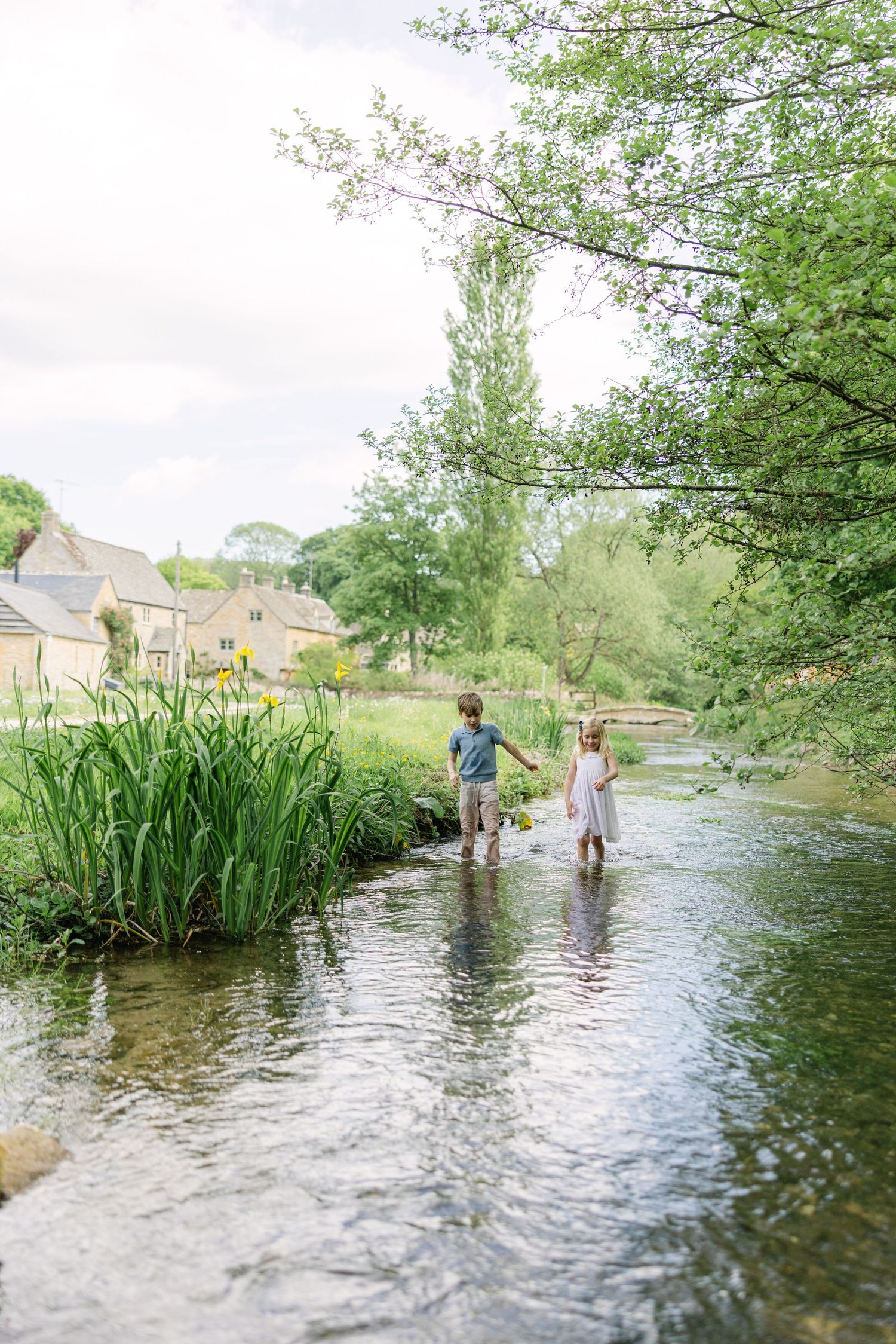 Boy and girl playing with paper boats during family photo session in the cotswolds