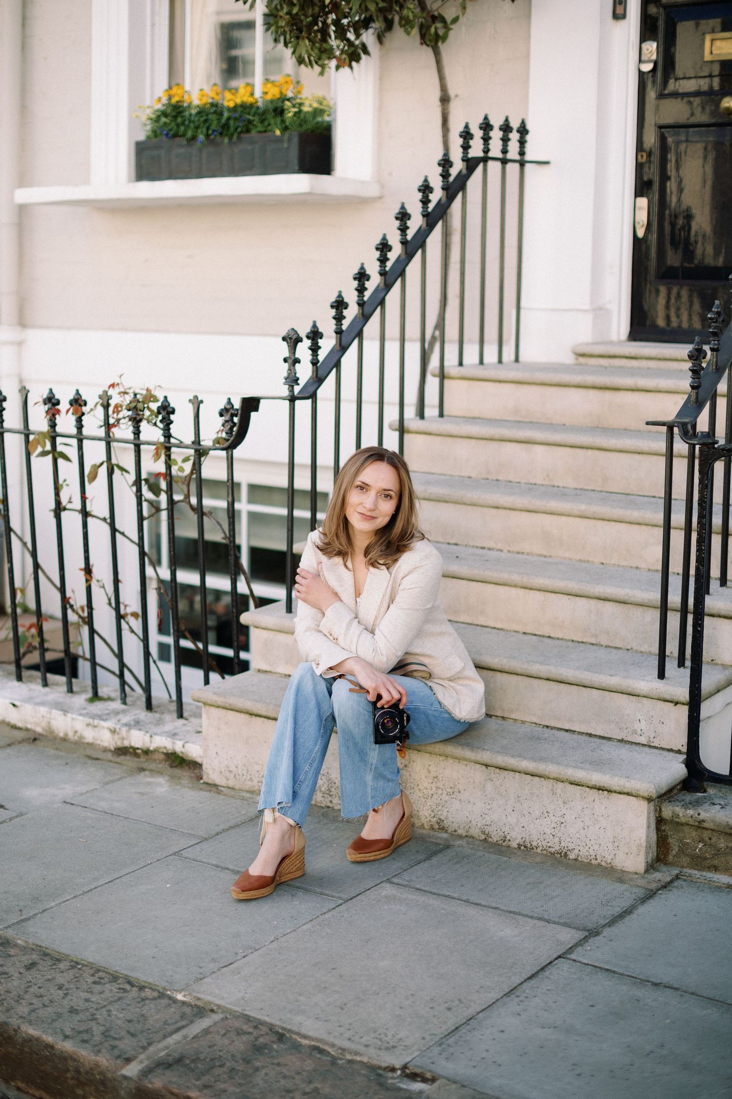 Miriam Caterina Wahl sitting on steps in front of a colourful house in Notting Hill holding her camera