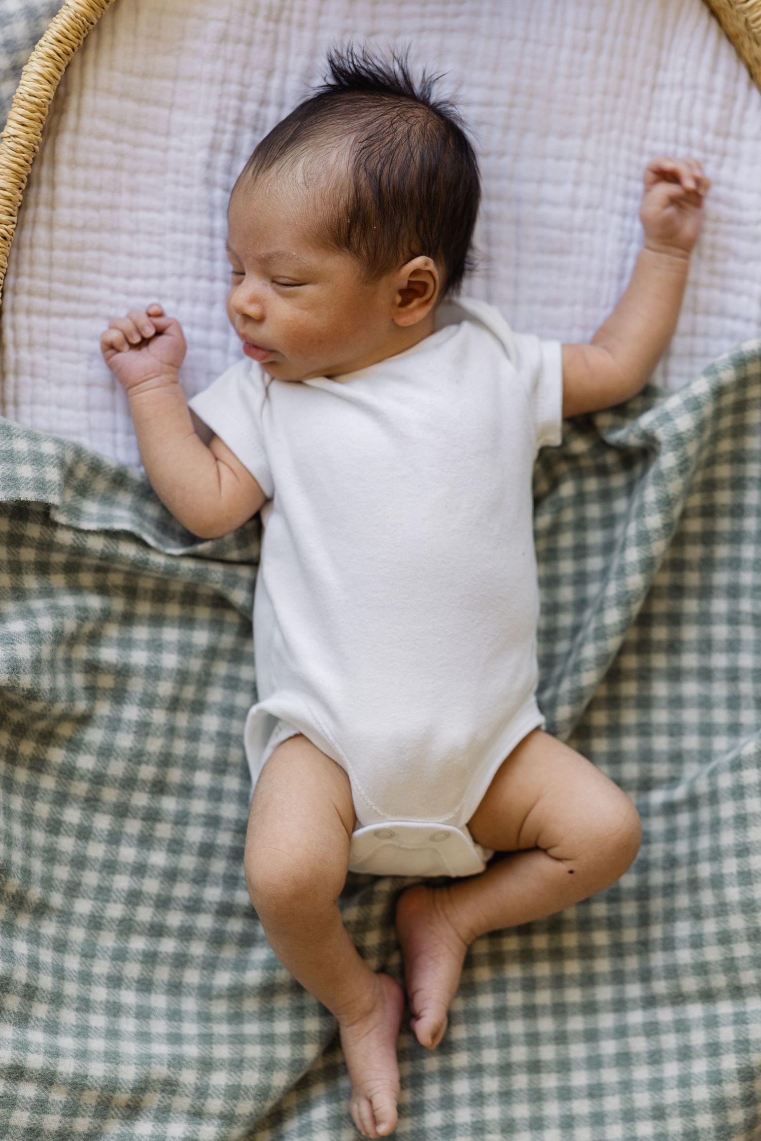 Newborn gently sleeping in moses basket during newborn session