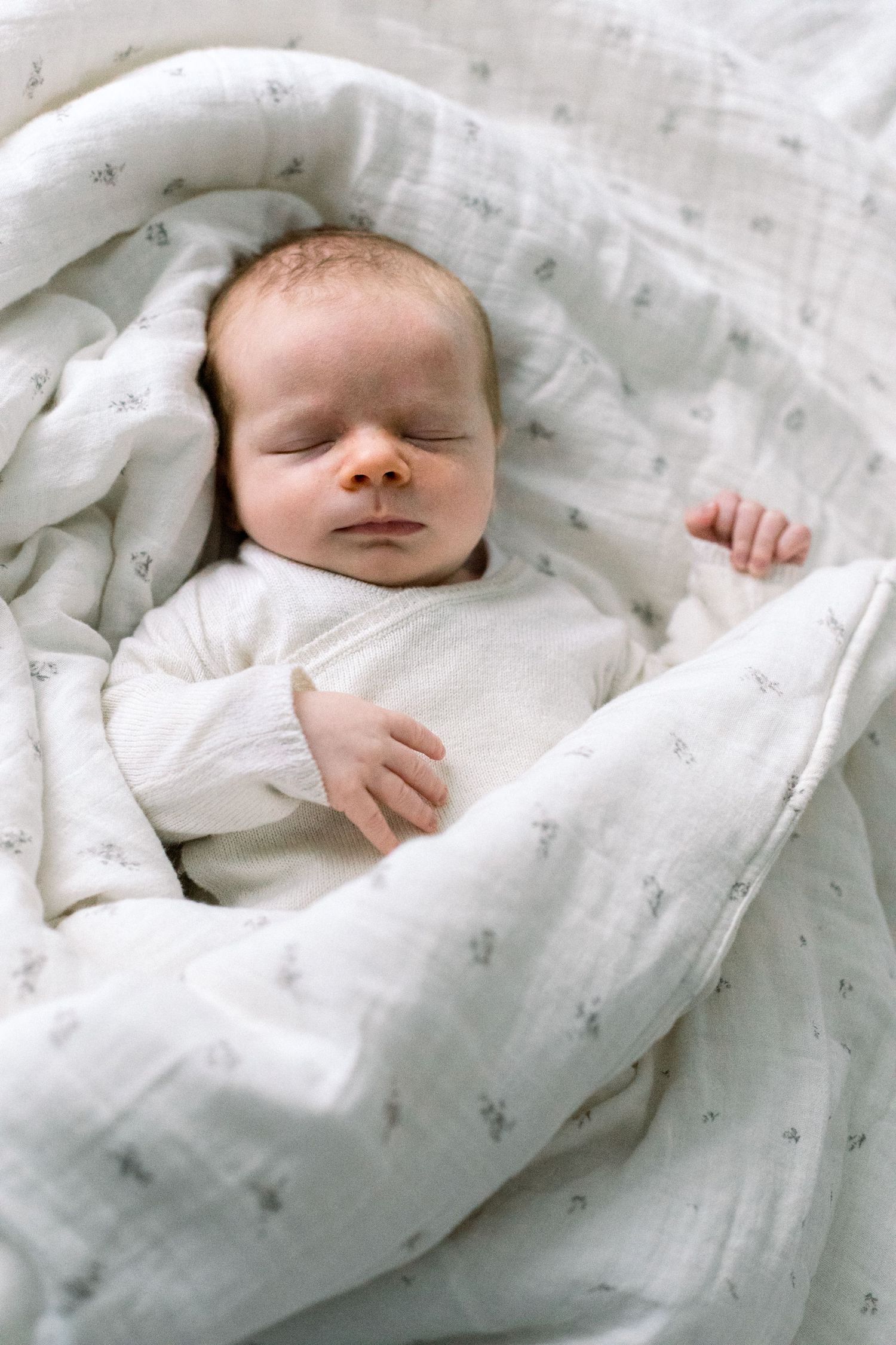 A newborn baby wrapped in soft fabric, lying peacefully - modern newborn photography london