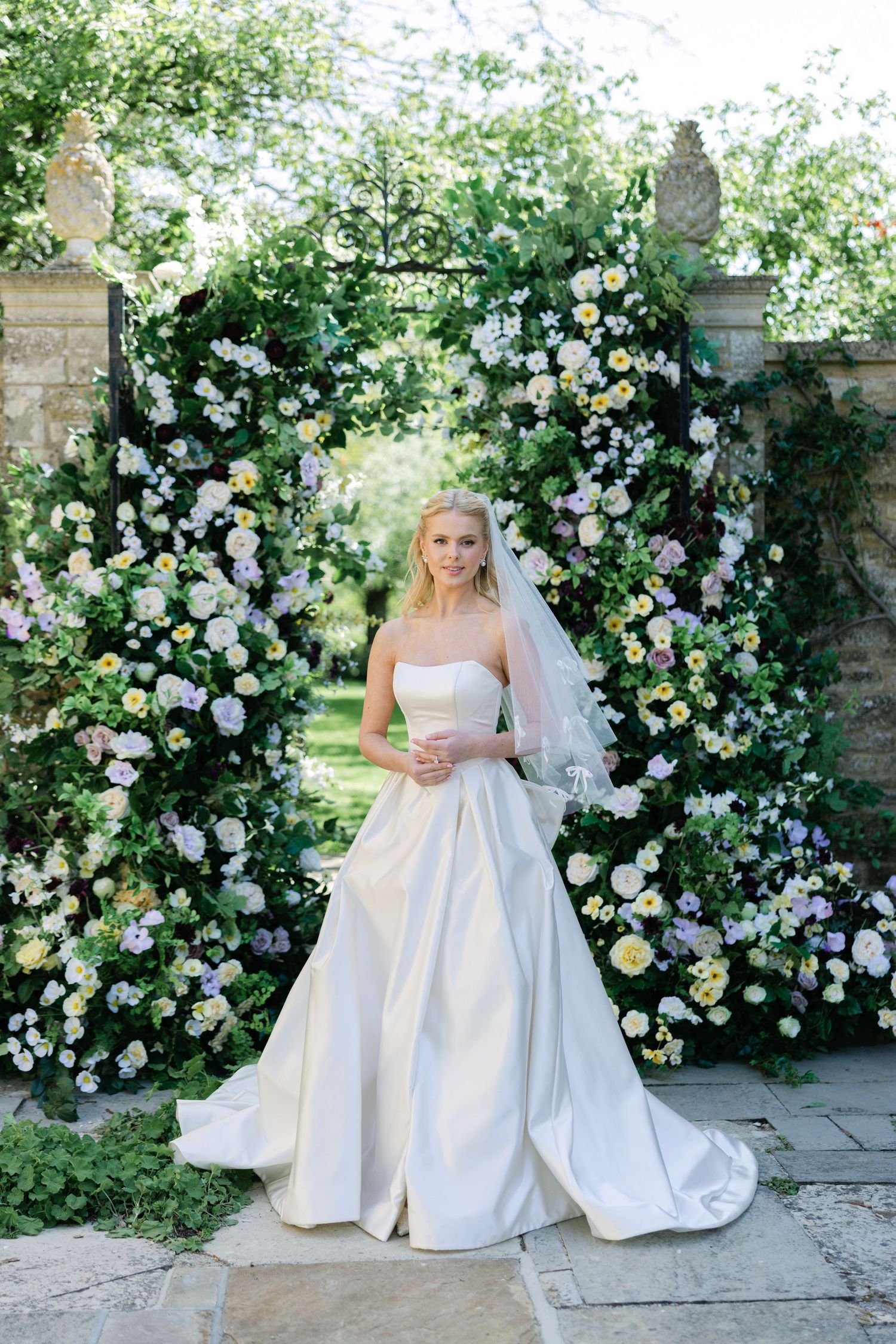 Bride infront of a flower archway at Cornwell Manor by Miriam Caterina Wahl