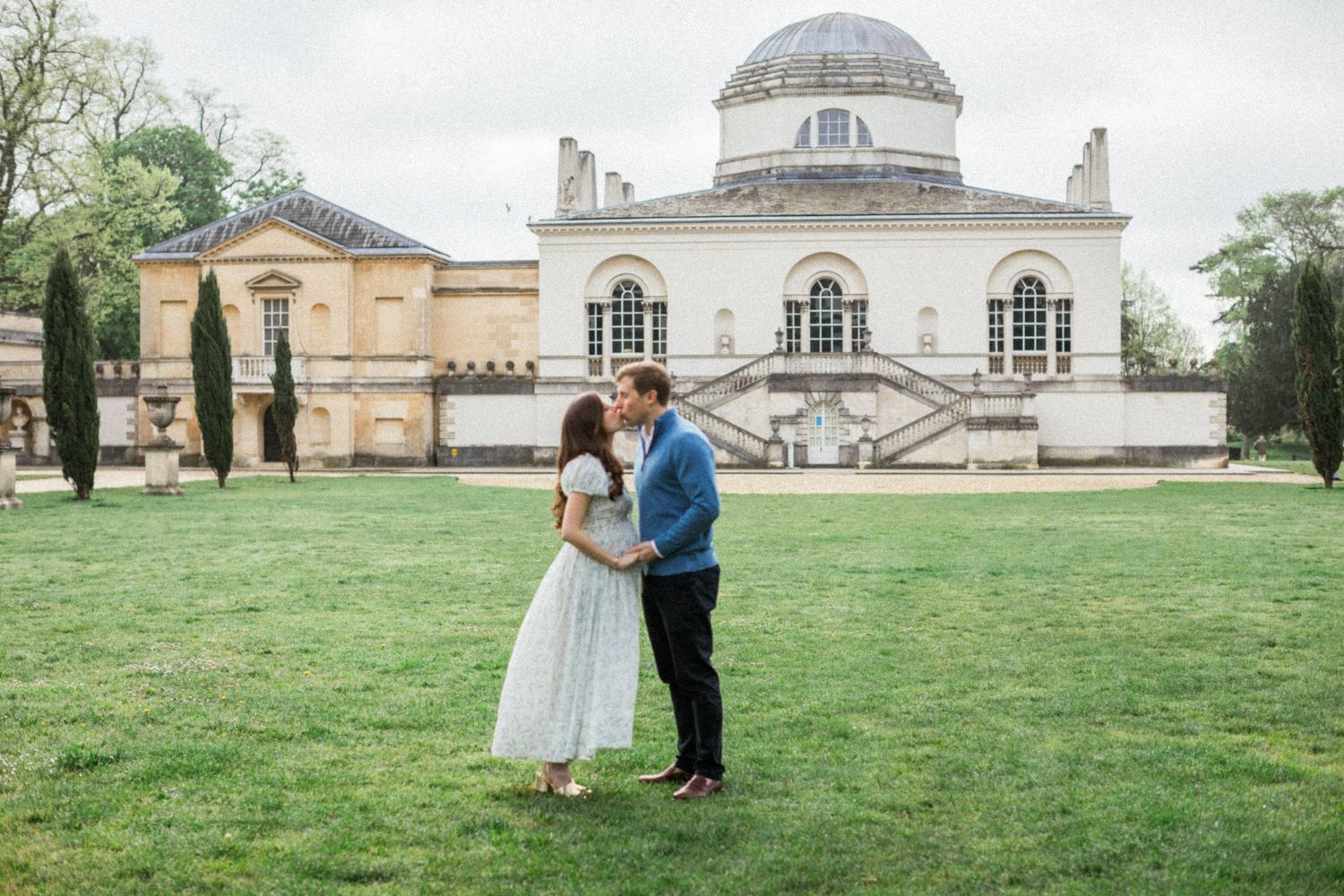 Pregnant woman kissing her husband infront of Chiswick House. Romantic maternity portraits by Miriam Caterina Wahl