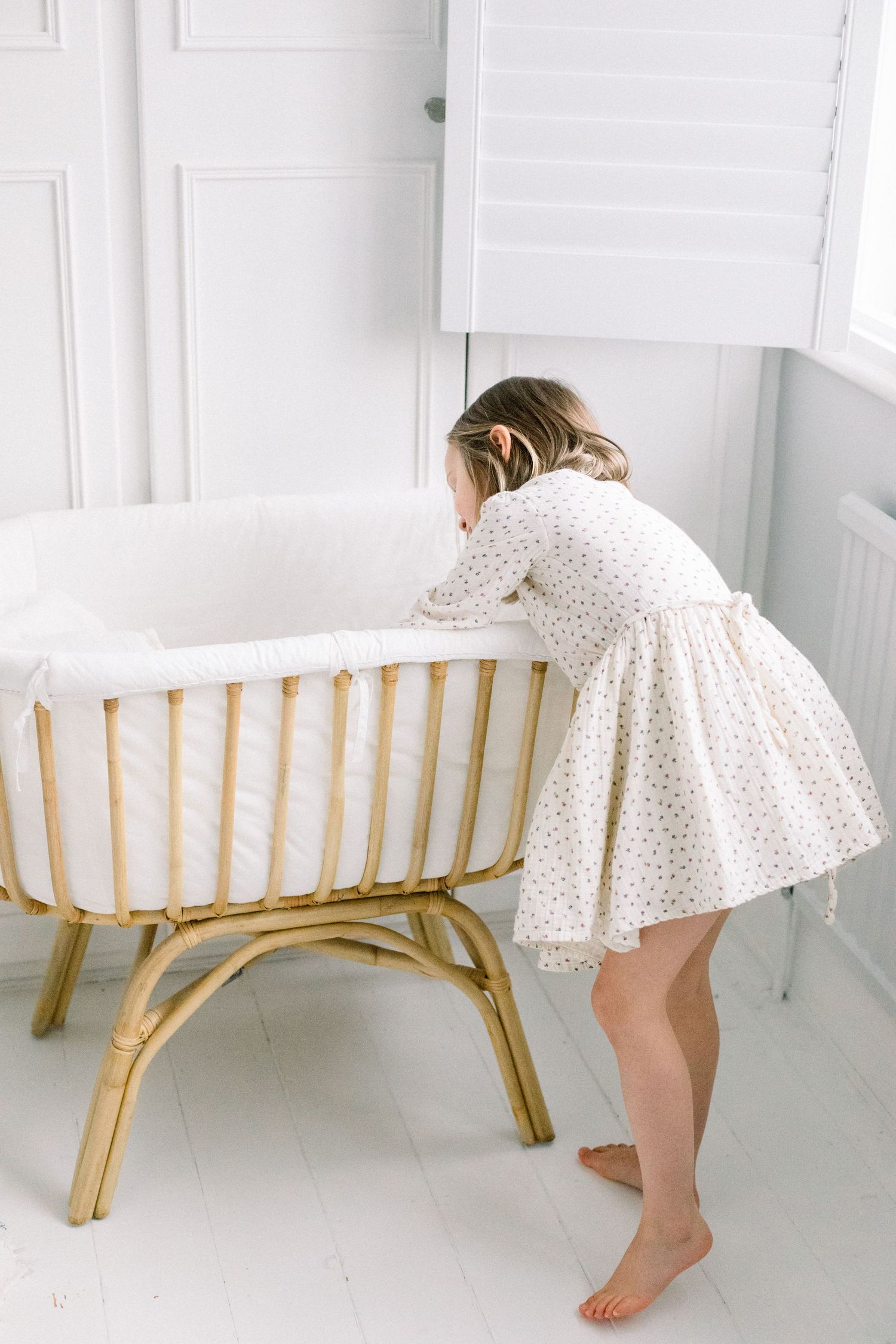 big sister looking into a baby crib