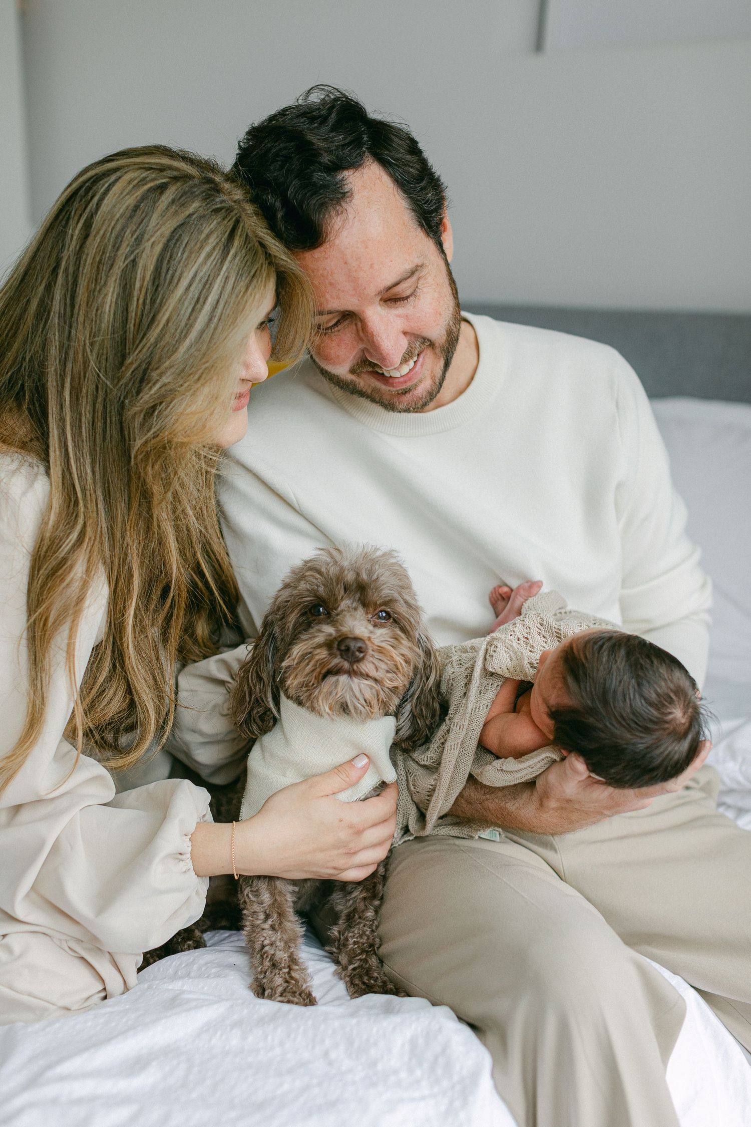 Mother and father looking dotting over their new baby with dog