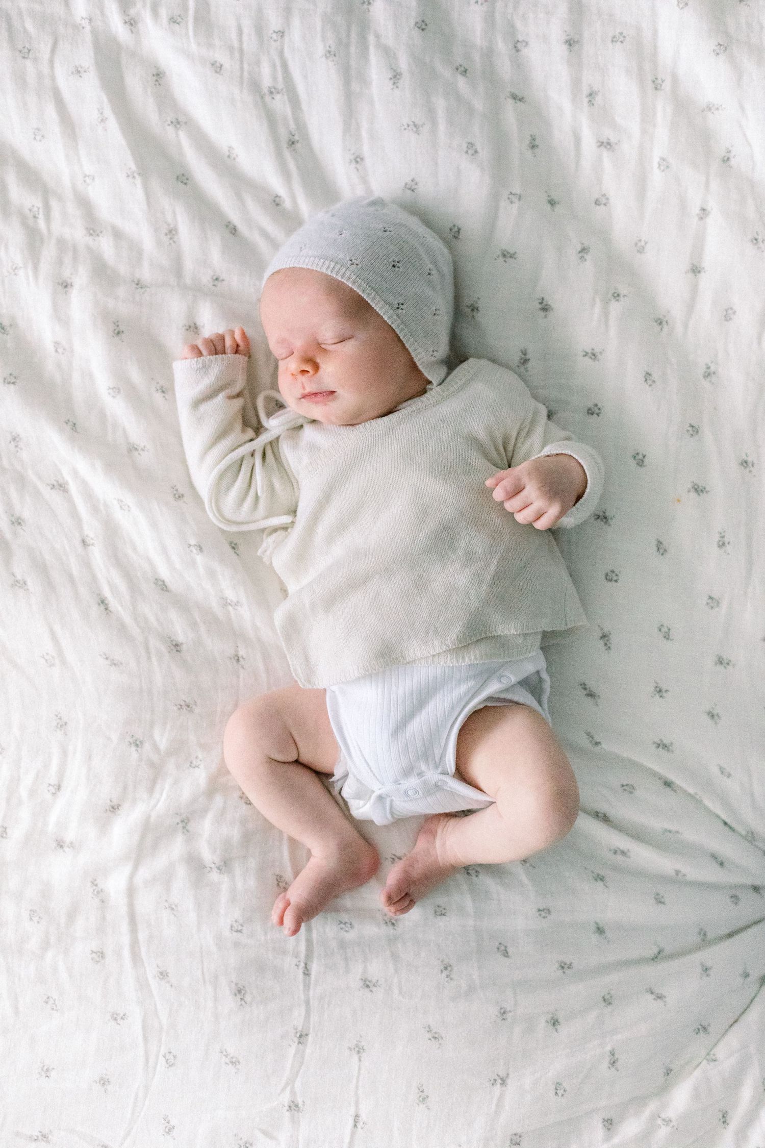 A newborn baby wrapped in soft fabric, lying peacefully on a bed - natural newborn photography london
