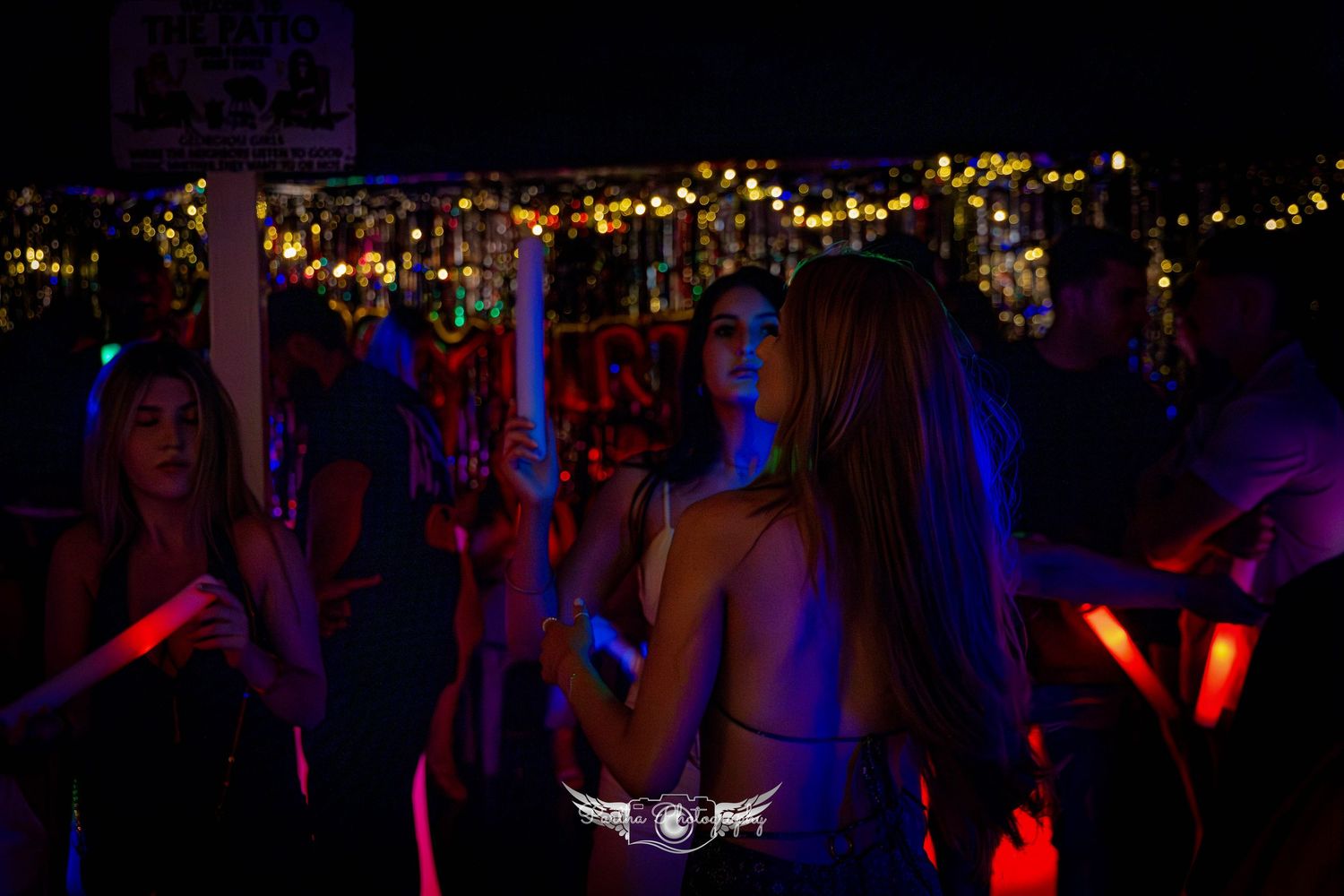 Party scene with string lights and dancers illuminated by blue and red lighting.