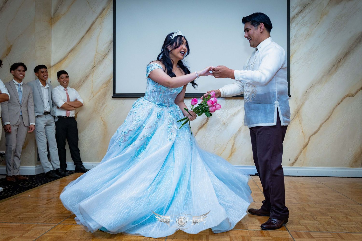 A couple dancing gracefully in formal attire on a wooden dance floor.