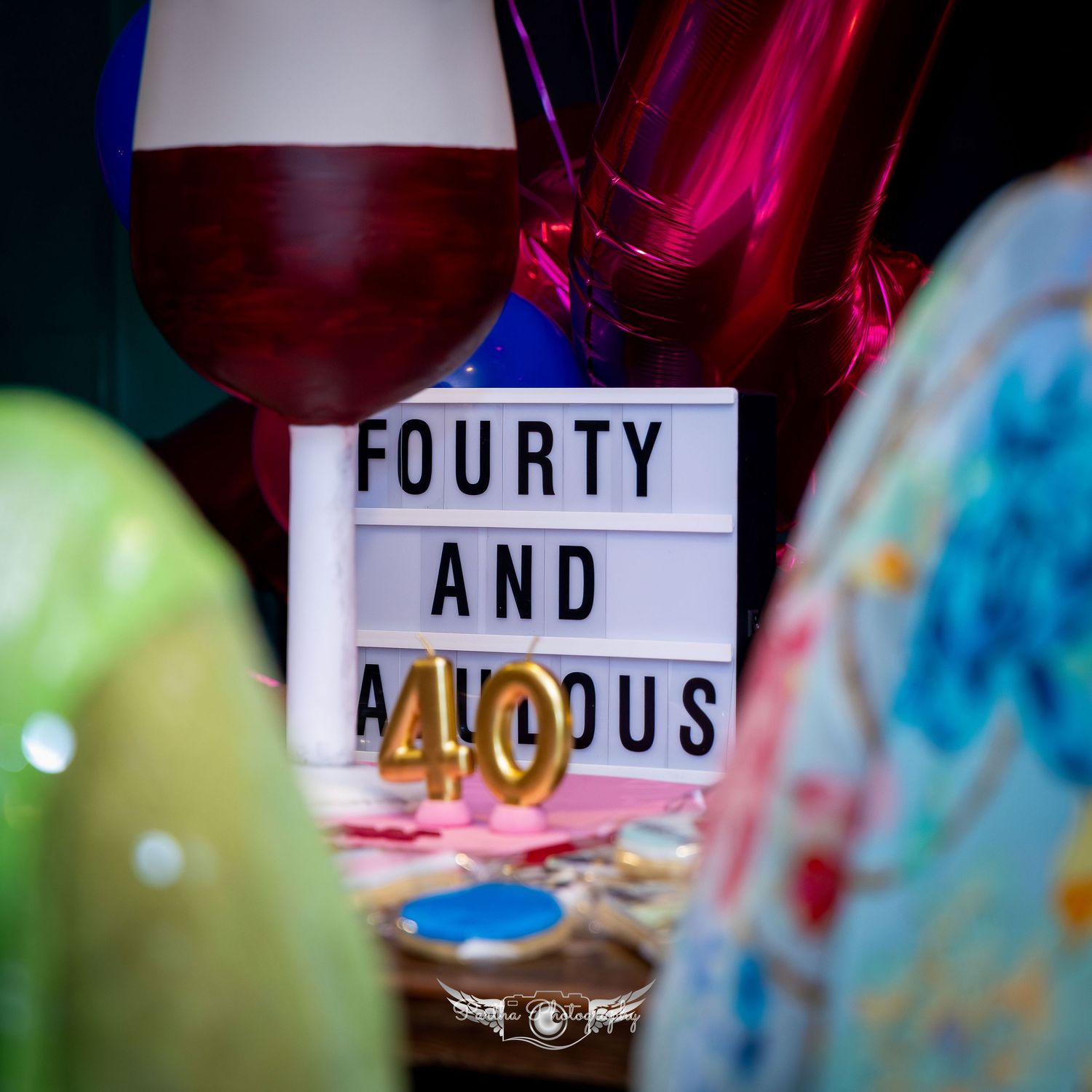 Decorative party signage with colorful balloons in the background.