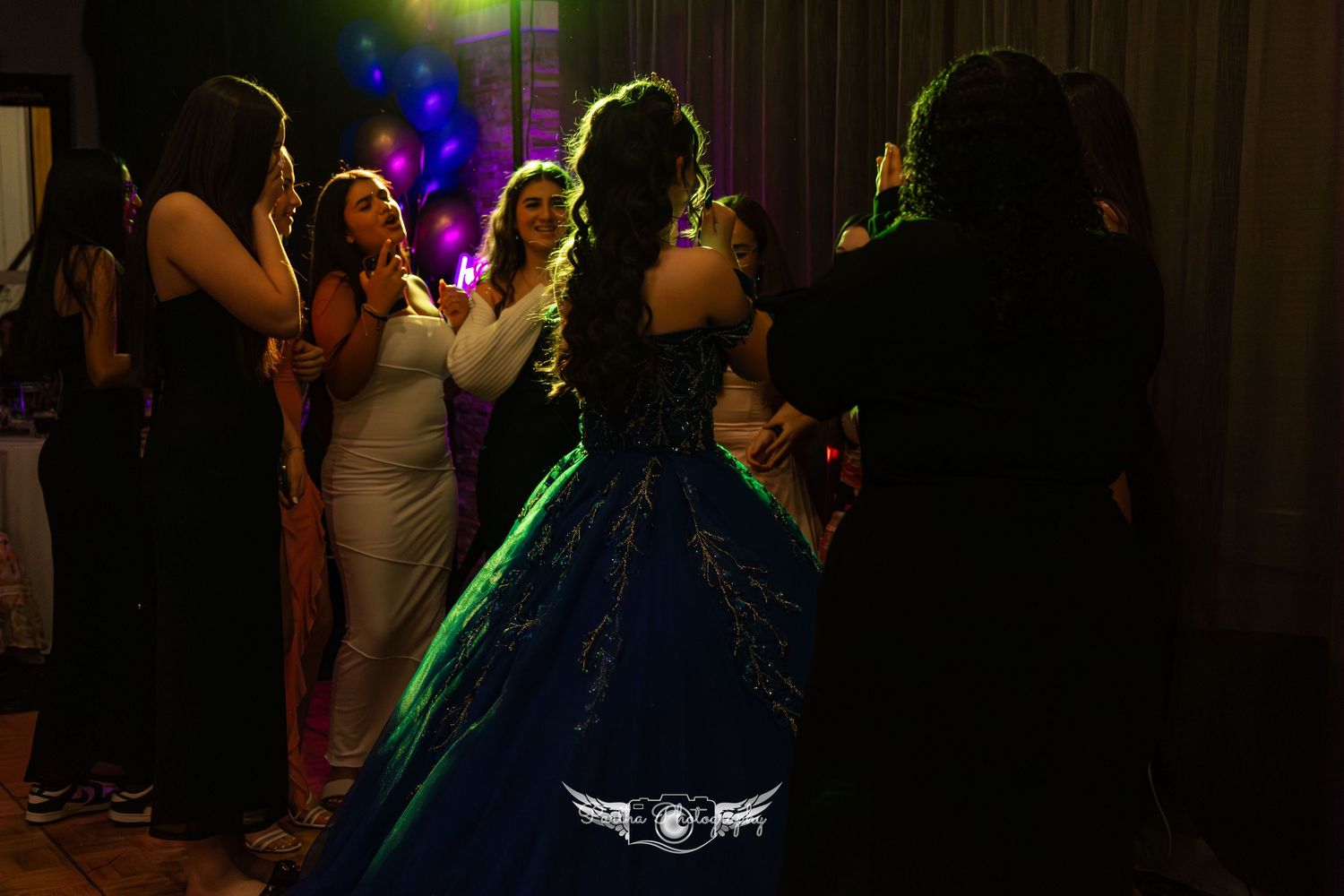 People dancing at a party with colorful disco lighting and dark ambiance.