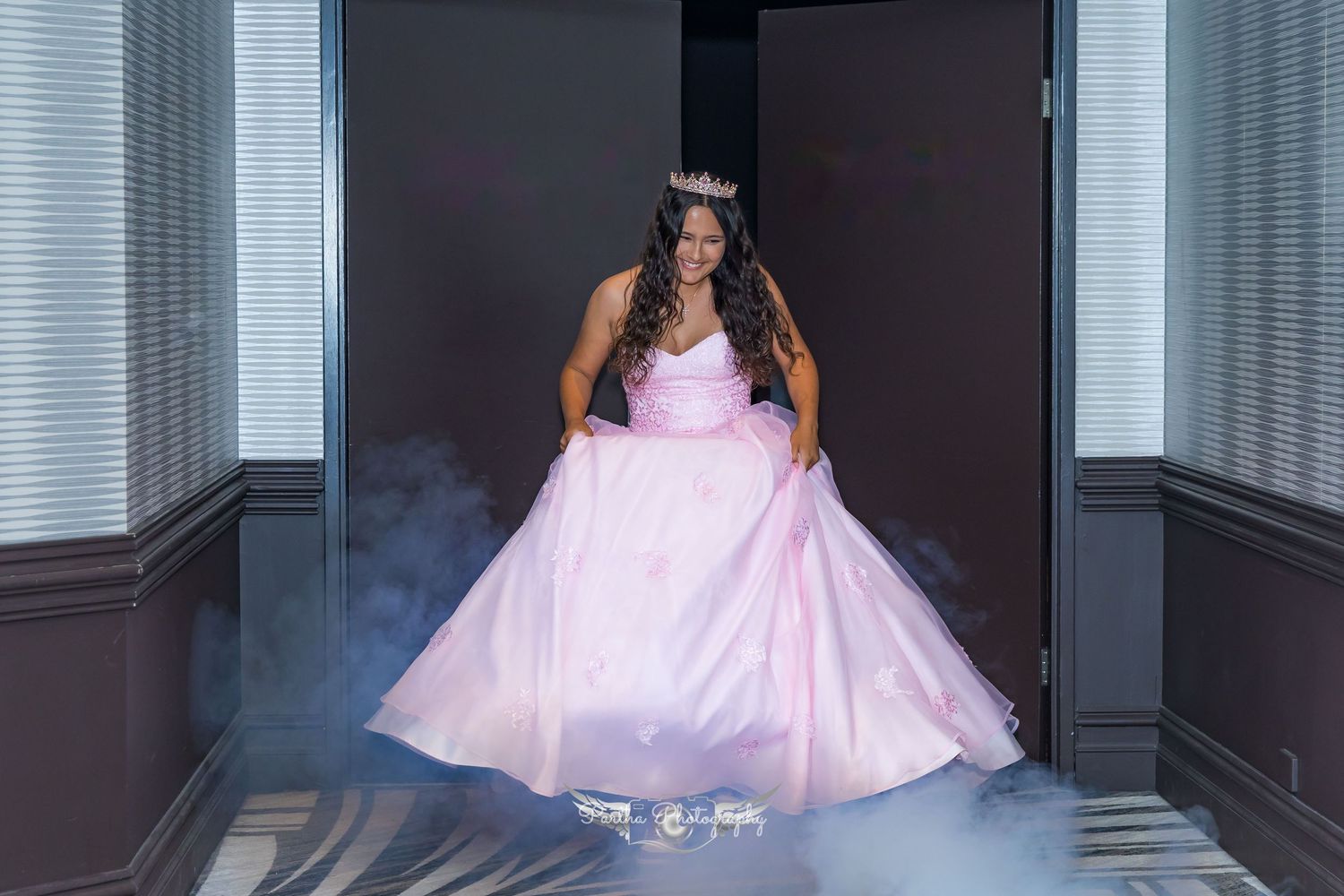 A pink ballgown dress photographed in a hallway with dramatic smoke effects.