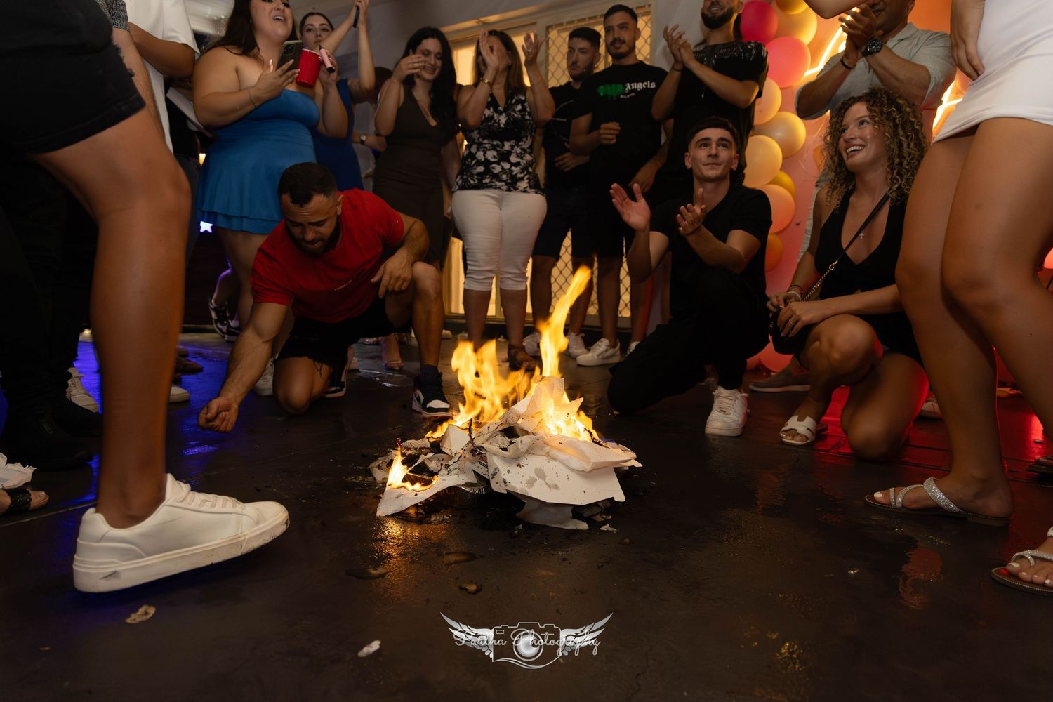 A group gathers around burning candles on the floor during what appears to be a celebration ritual.