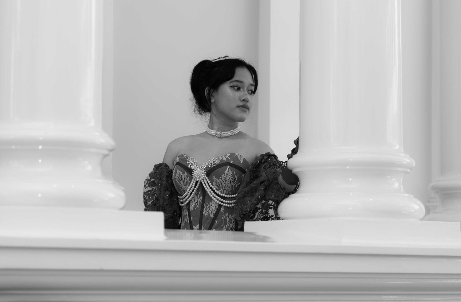 Elegant person in a dramatic pose against white columns and holiday decorations.