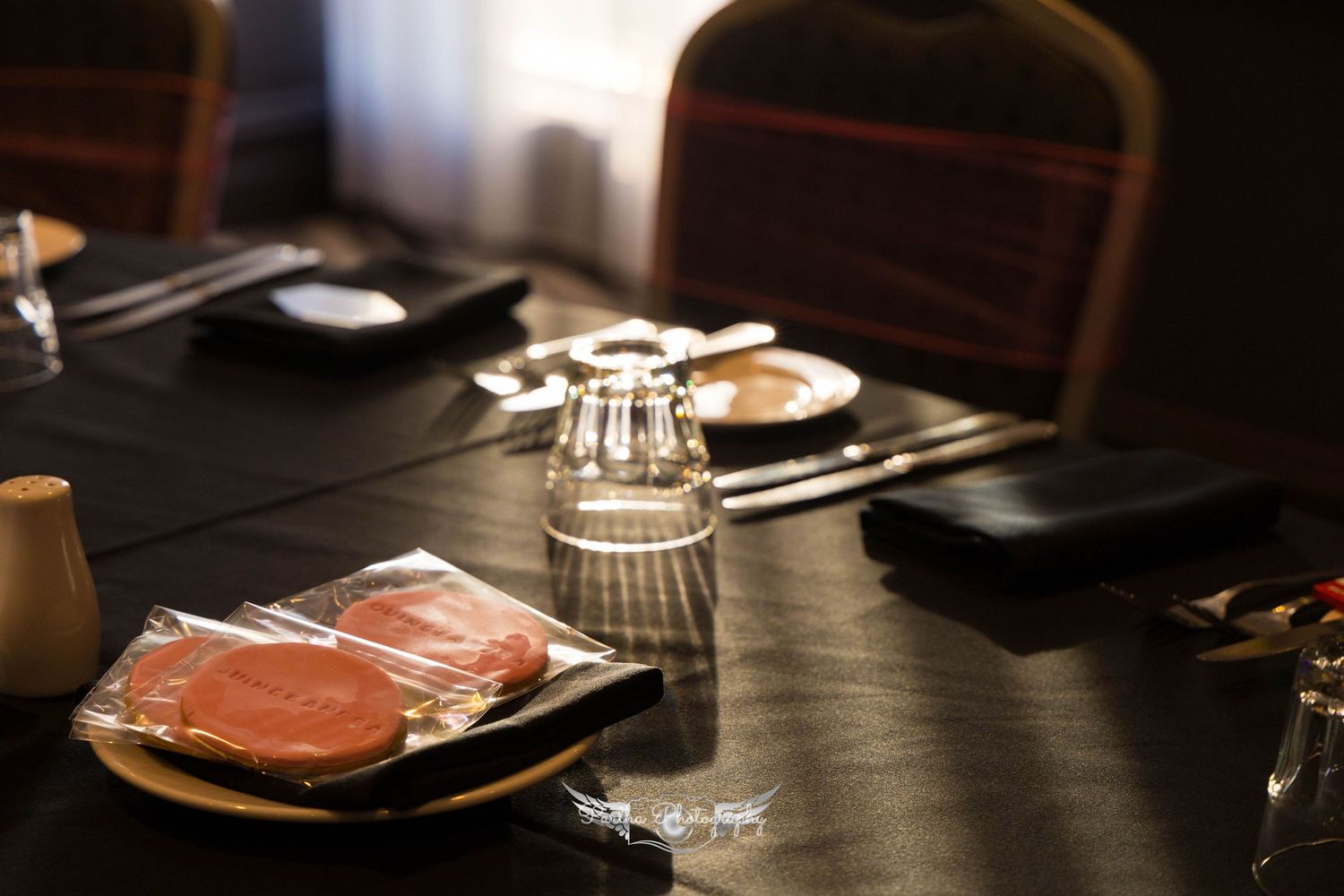 Place settings on a dark table with plates and glassware for a formal dinner.