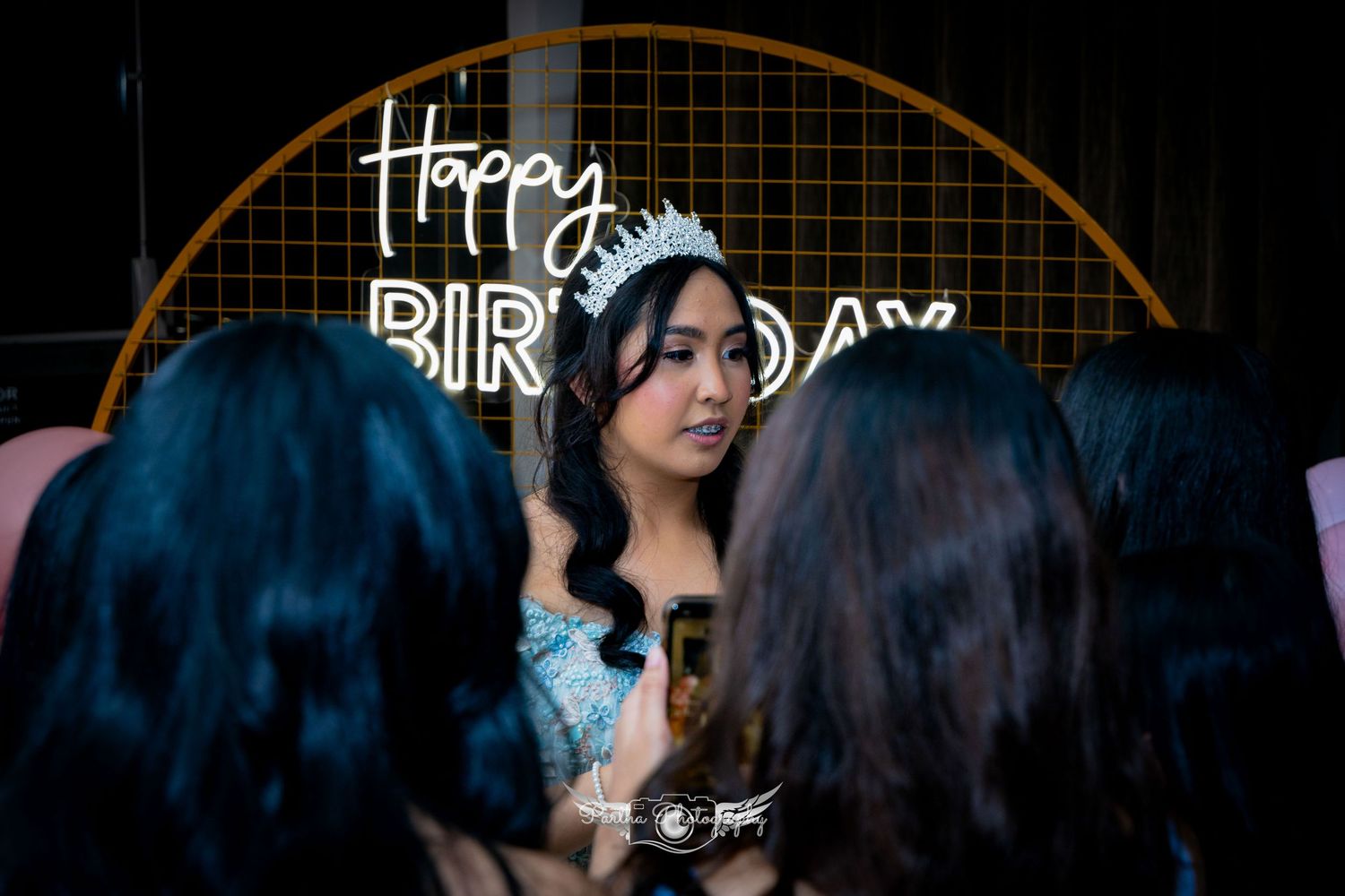 Birthday celebration setup with neon signage and balloon decorations.