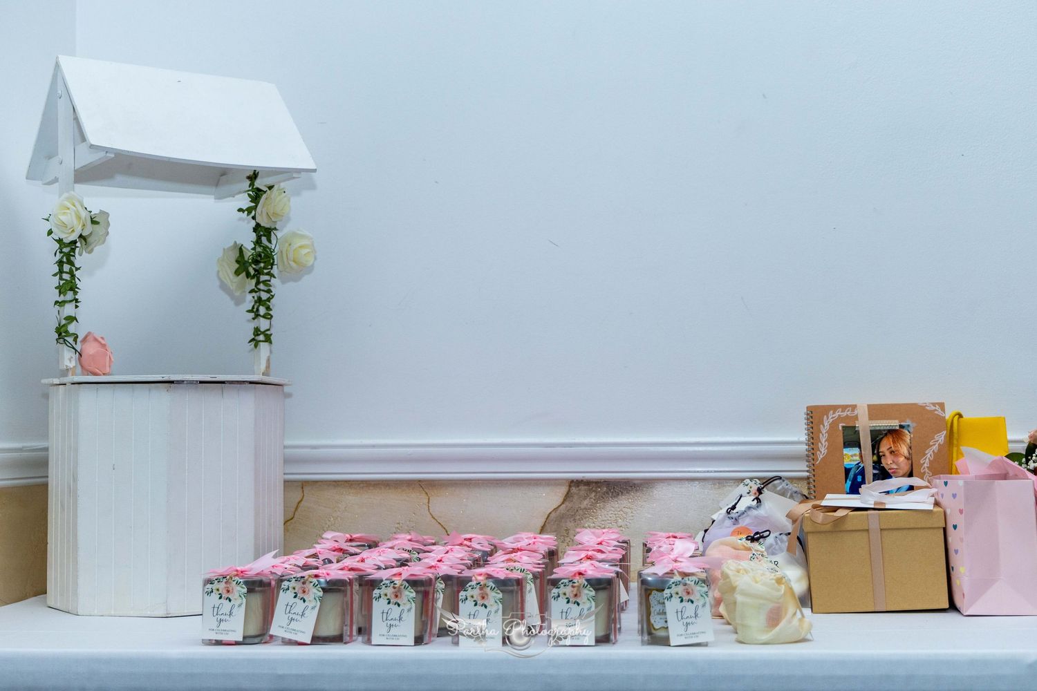 White decorative wedding stand with floral arrangements and party favor jars displayed on a table.