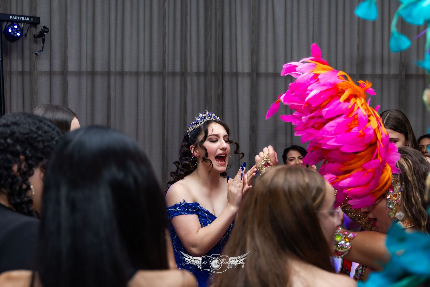 Celebratory scene with performers and guests enjoying a festive moment with bright feathered costumes.