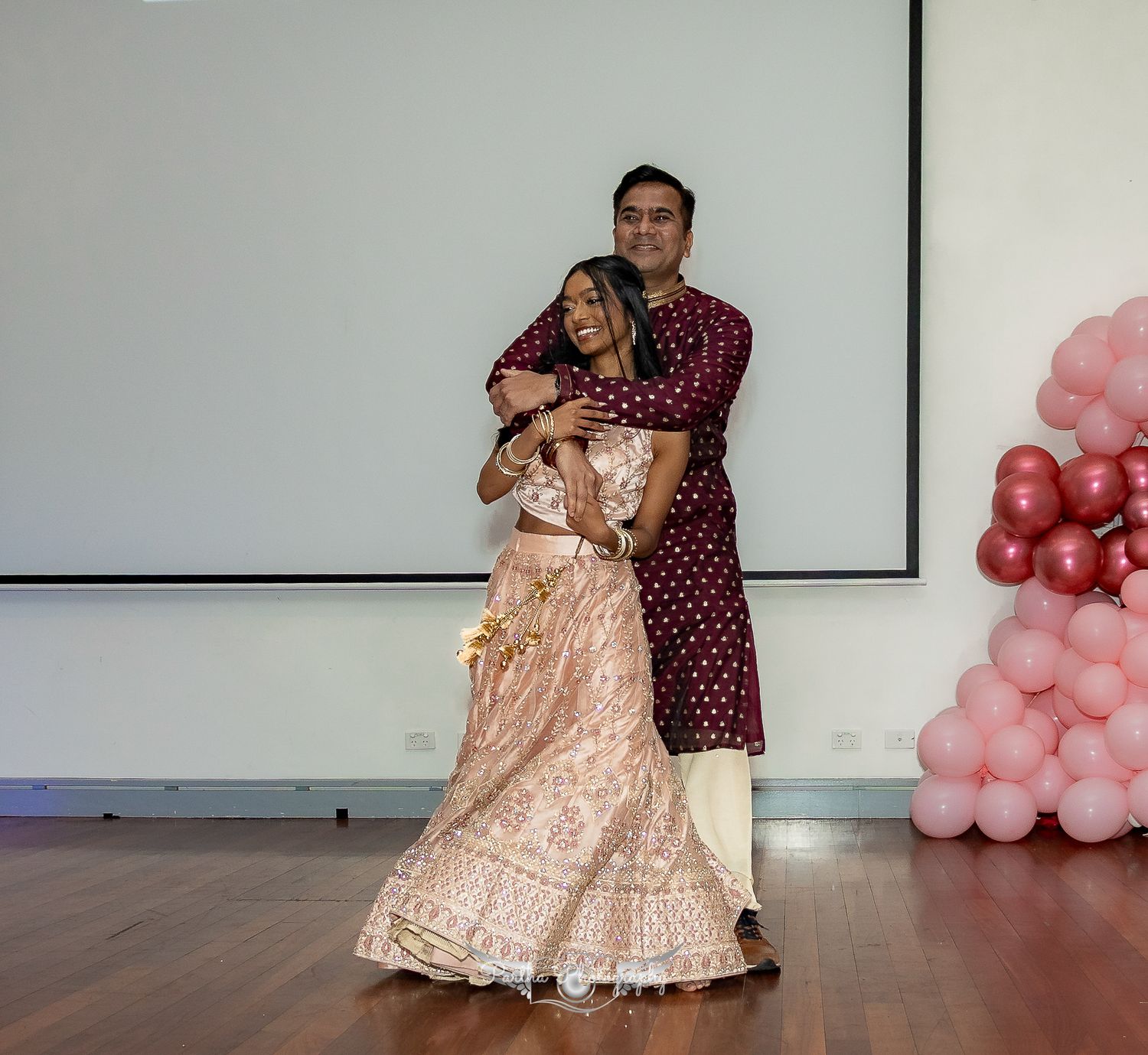 Couple dancing together at a party decorated with pink balloons.