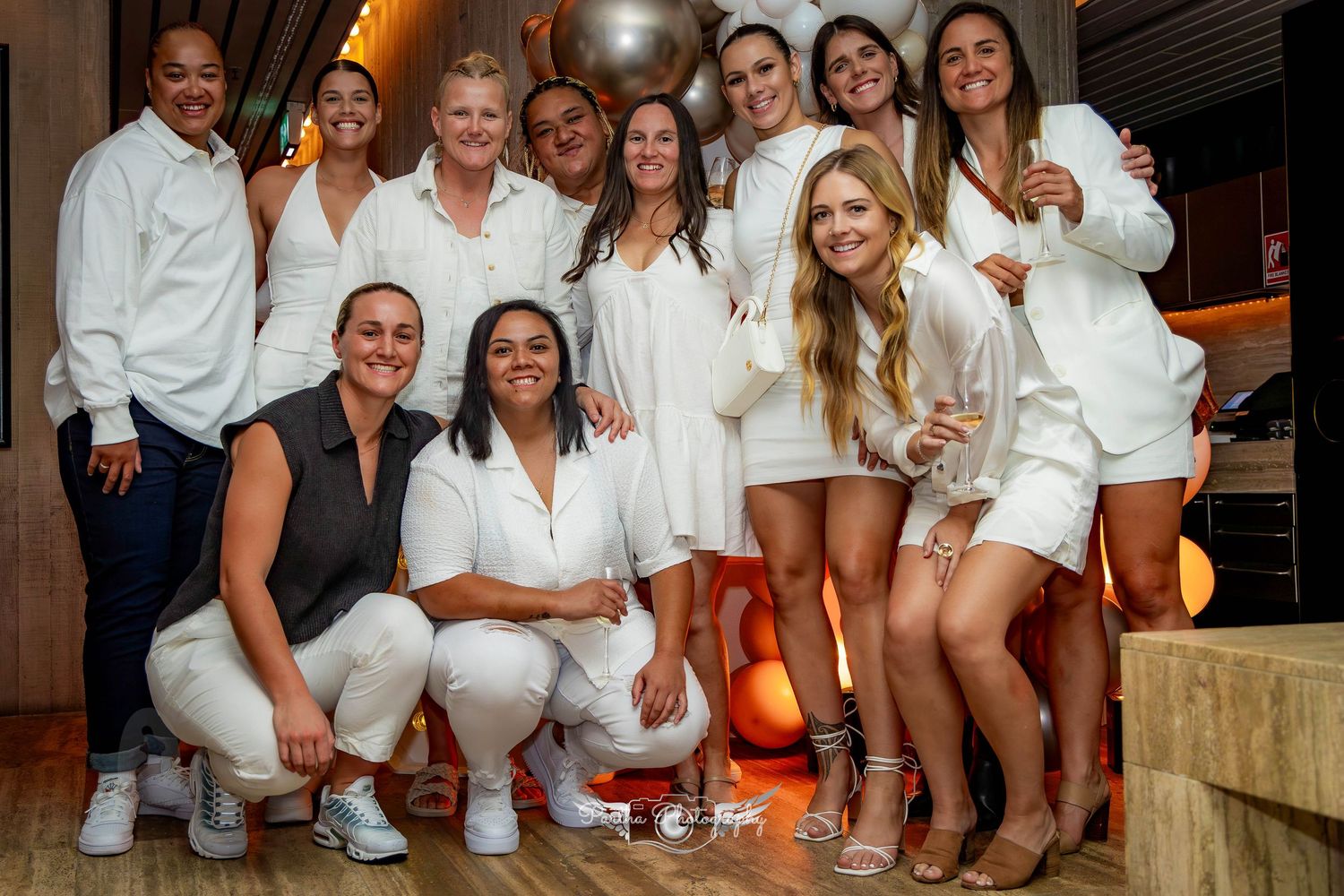Group photo of people dressed in white at an elegant party setting.