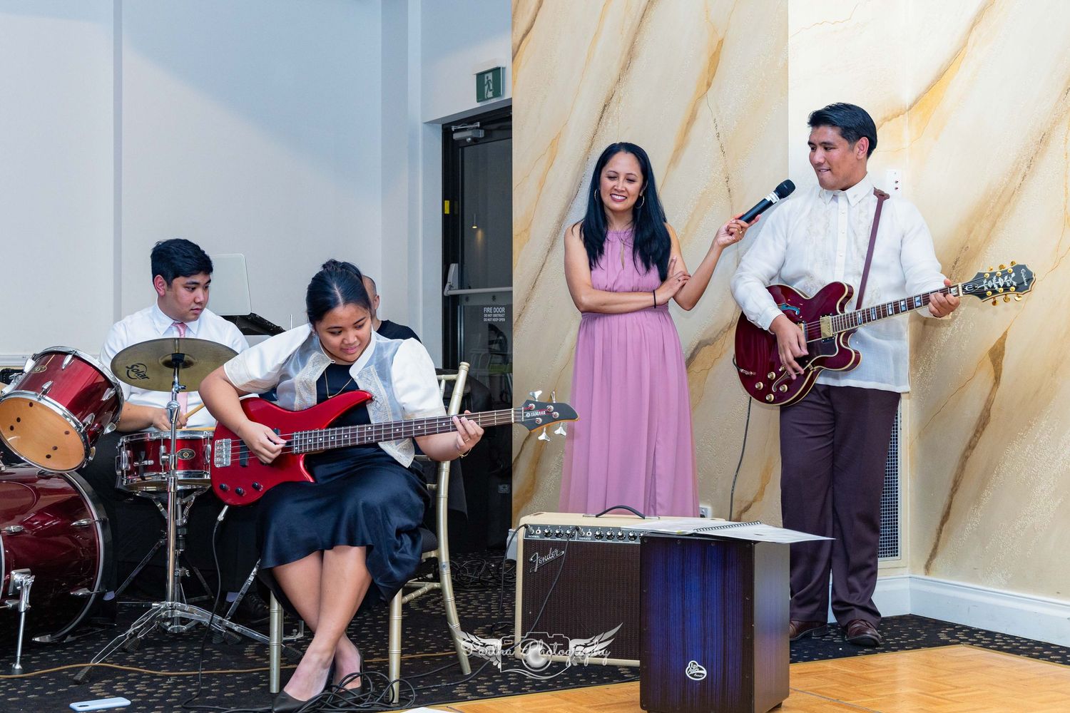 A band performs on stage with musicians playing instruments including drums and guitar.