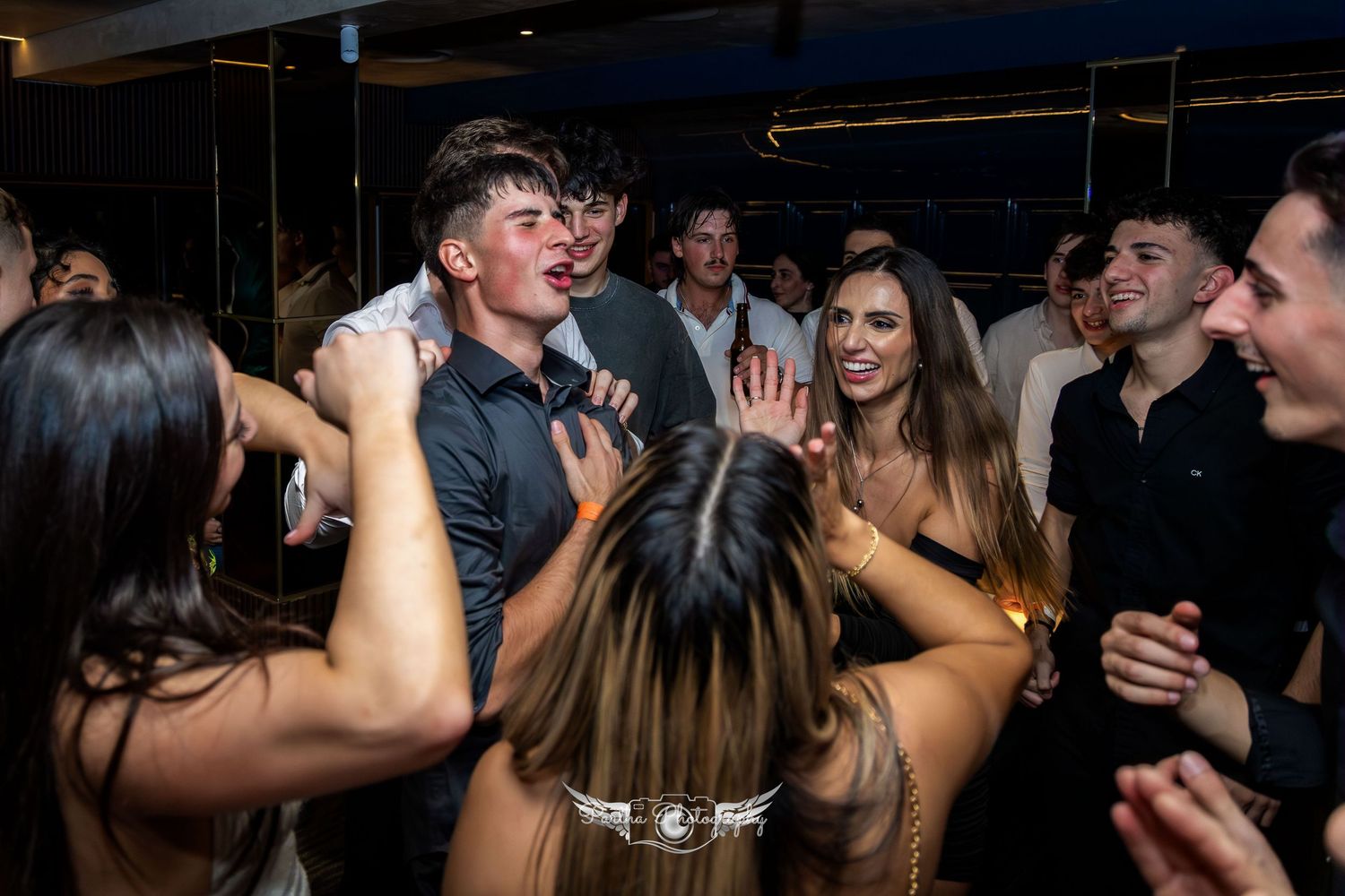 Enthusiastic group dancing and singing together at a nightclub celebration.
