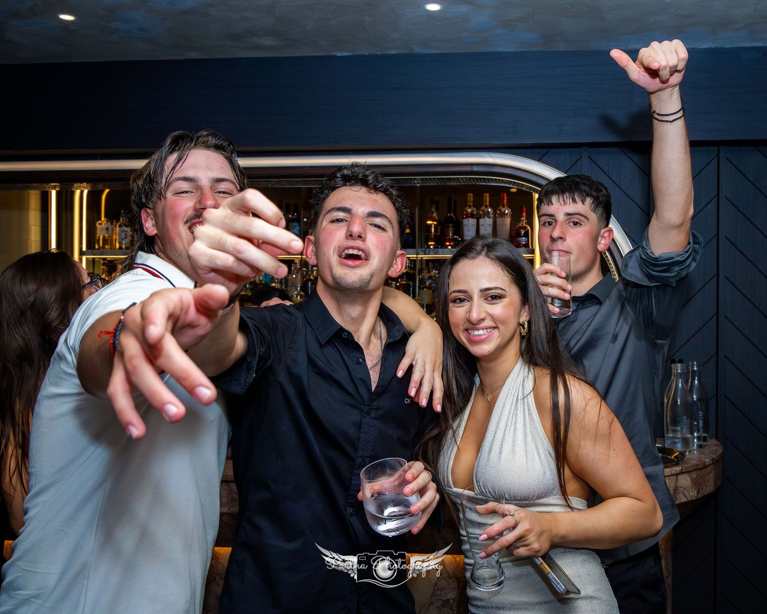 Group of friends celebrating with drinks and high energy at a nightclub.
