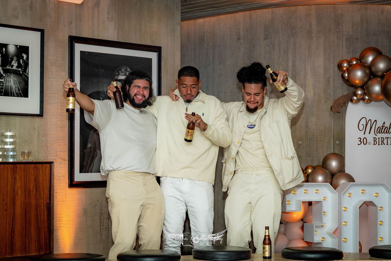 Group photo of people in cream colored outfits posing at a celebration event.