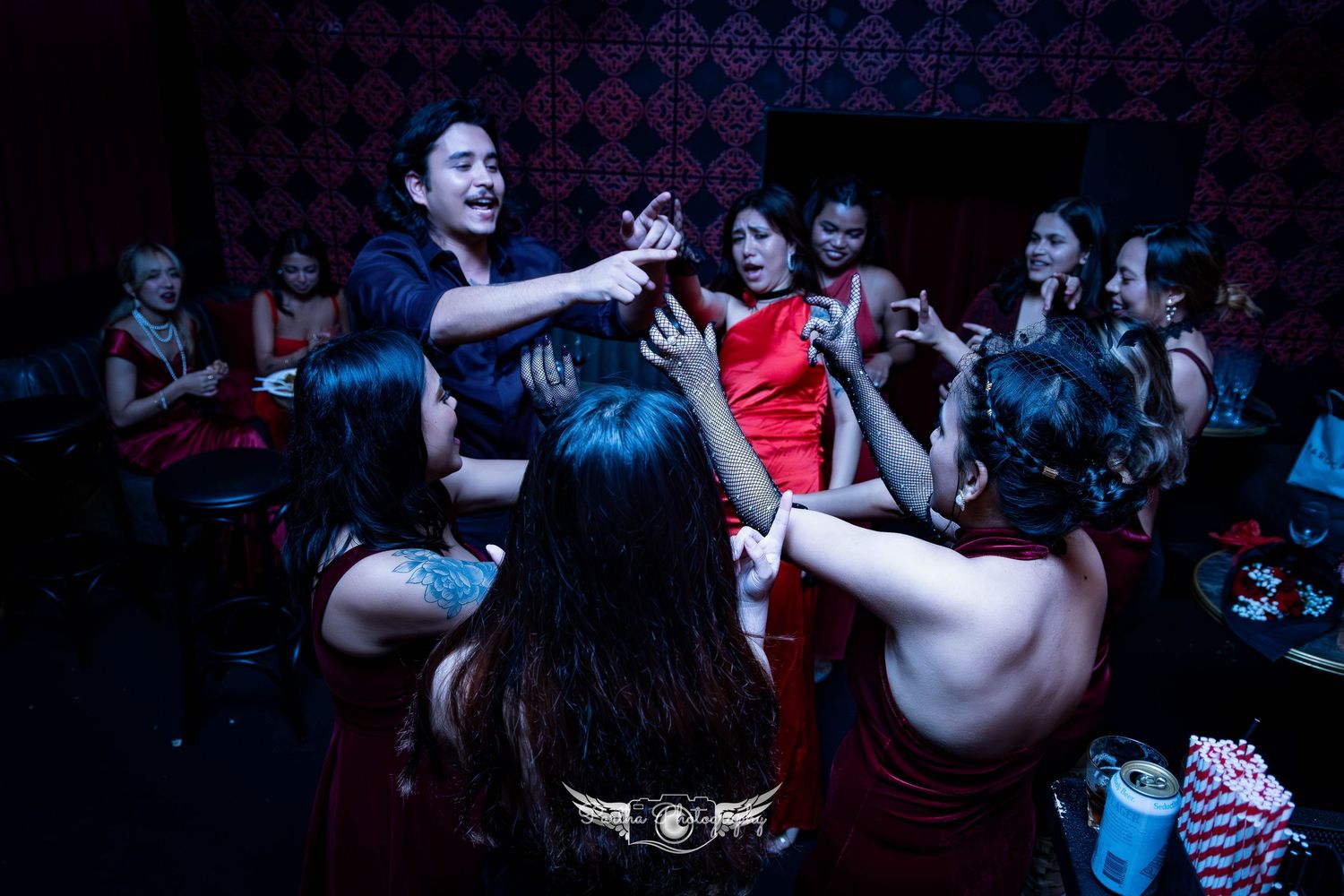 Energetic crowd dancing and interacting at a dimly lit nightclub with decorative wallpaper.