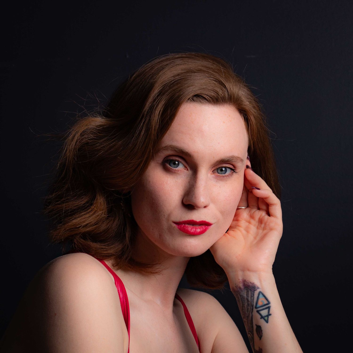 Portrait against dark background showcasing red lips and dramatic lighting.