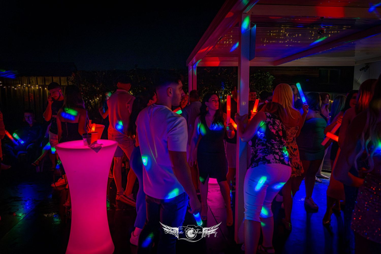 People dancing in a dark room illuminated by blue and red lights at a party.