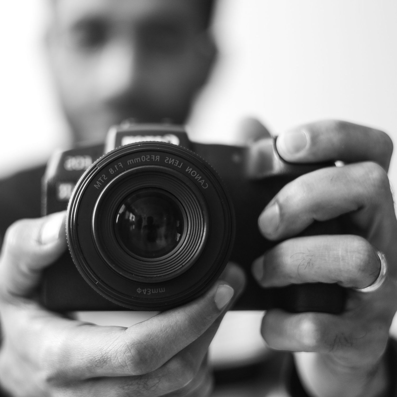Black and white close-up of photographer holding professional camera with lens.