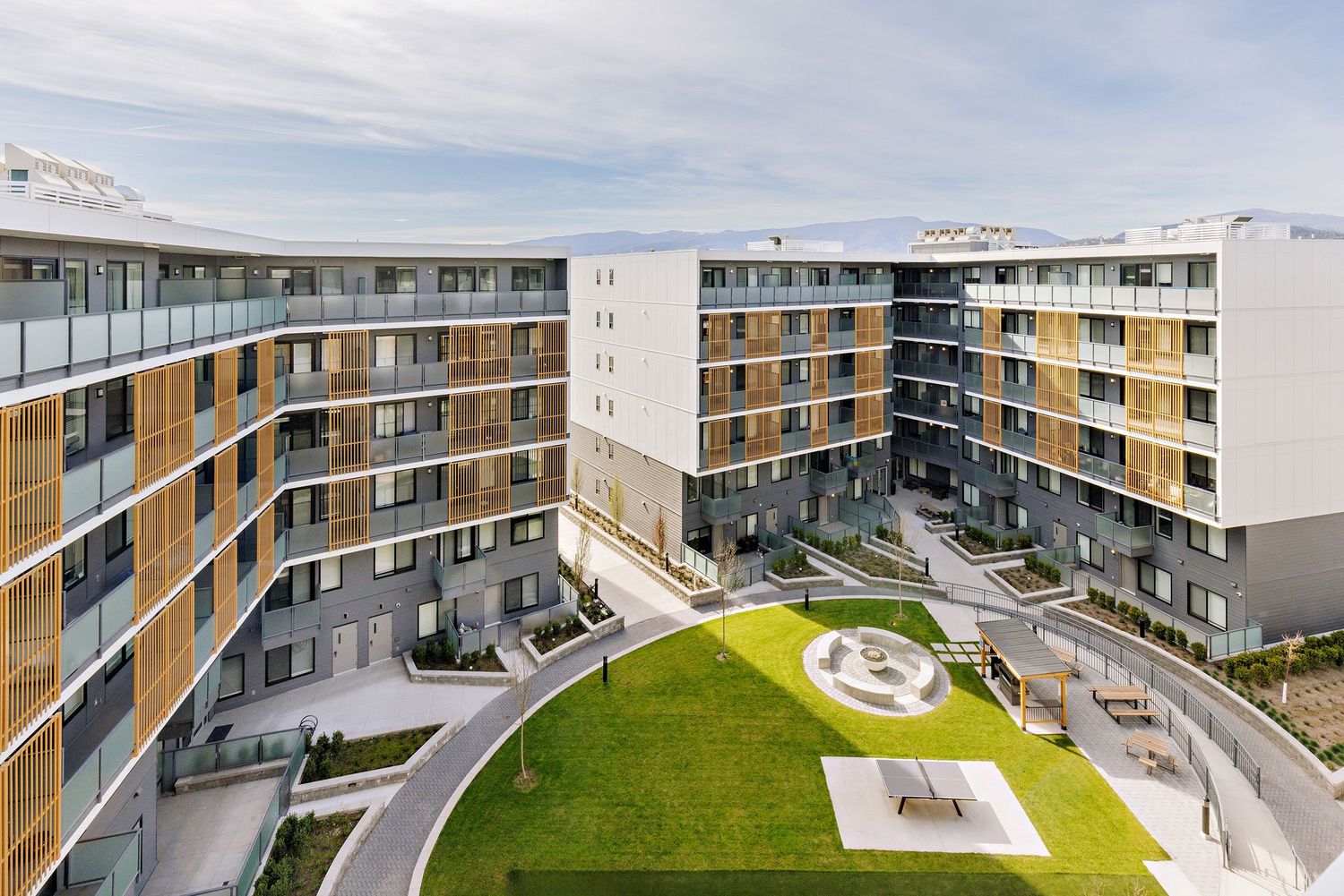 Modern apartment complex with curved architecture featuring a green courtyard and contemporary residential buildings.