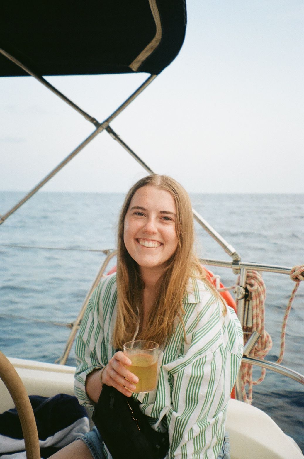 Person enjoying drink on sailboat deck during ocean cruise.
