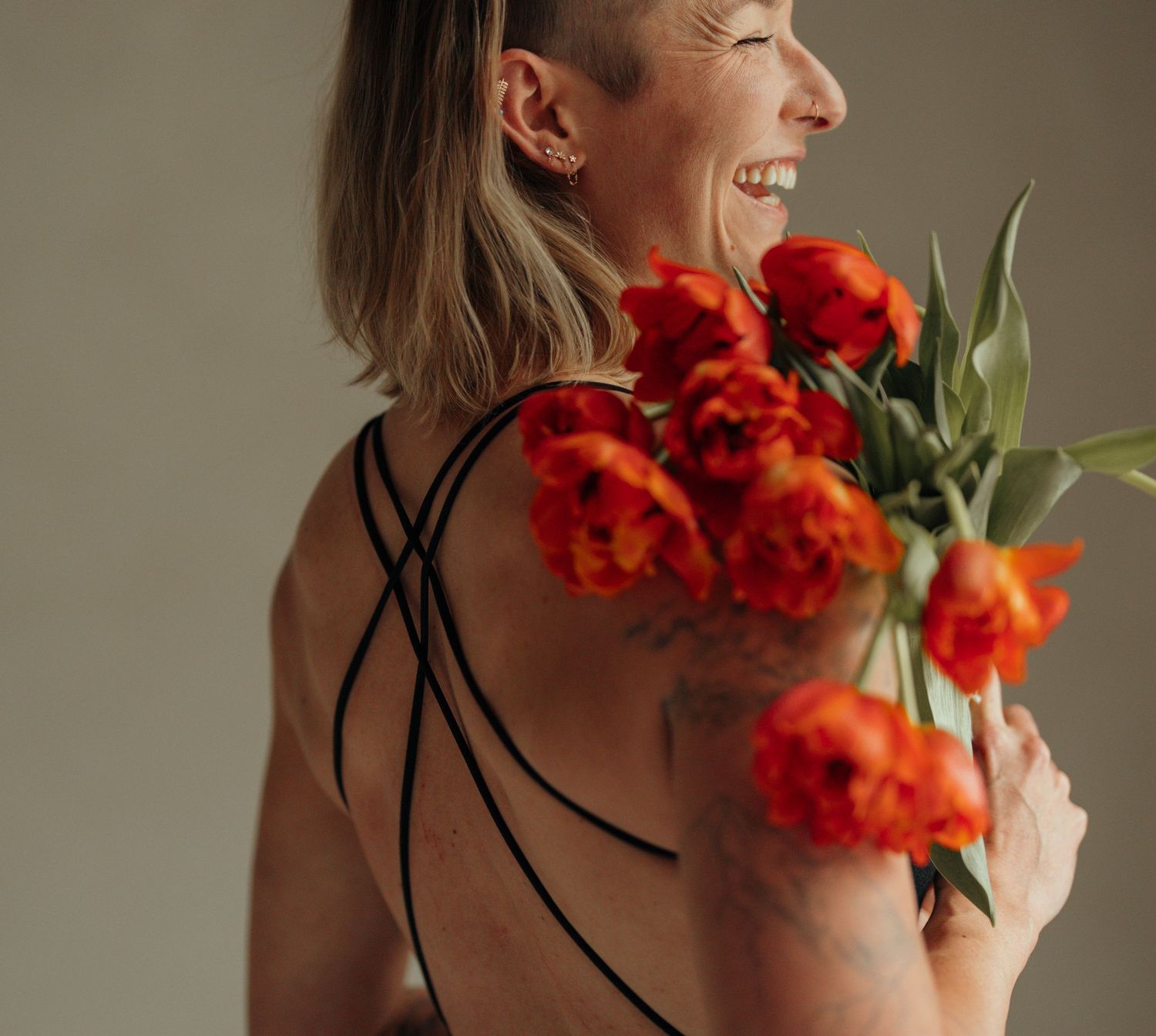 A joyful candid moment captured from behind showing vibrant red tulips against a strappy black top.