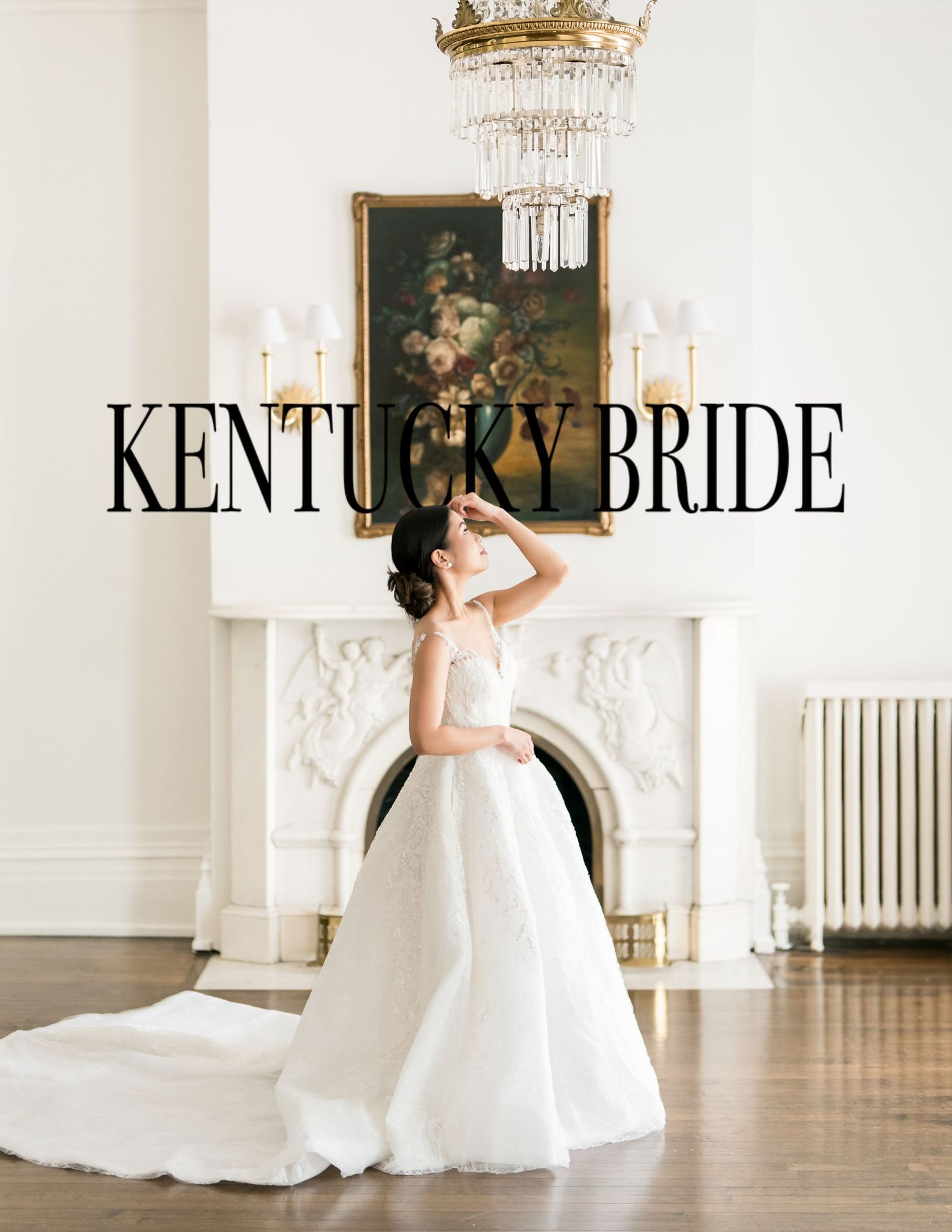 Elegant bridal photo featuring a white ballgown wedding dress in an ornate room with antique fireplace and crystal chandelier.