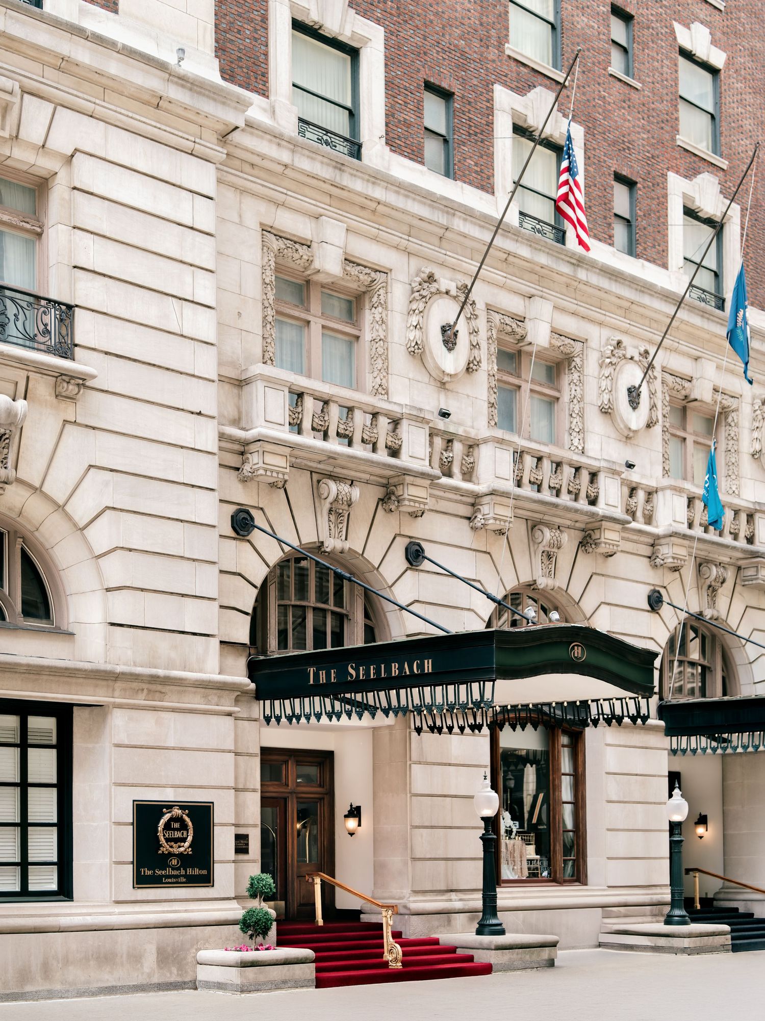 Elegant historic hotel building exterior with red brick facade and black awnings along The Benjamin entrance.