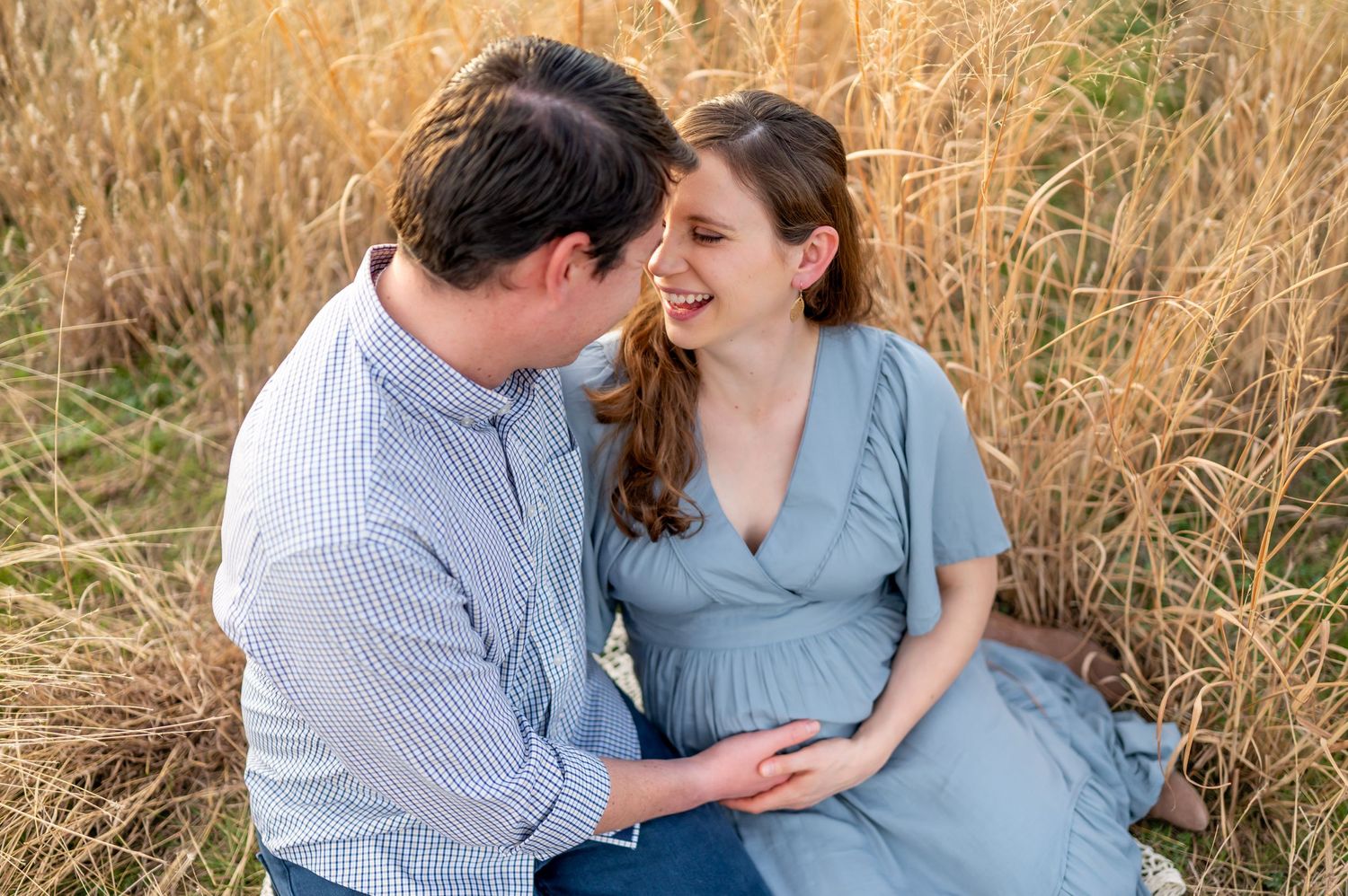 Couple sharing intimate moment in tall grass field.