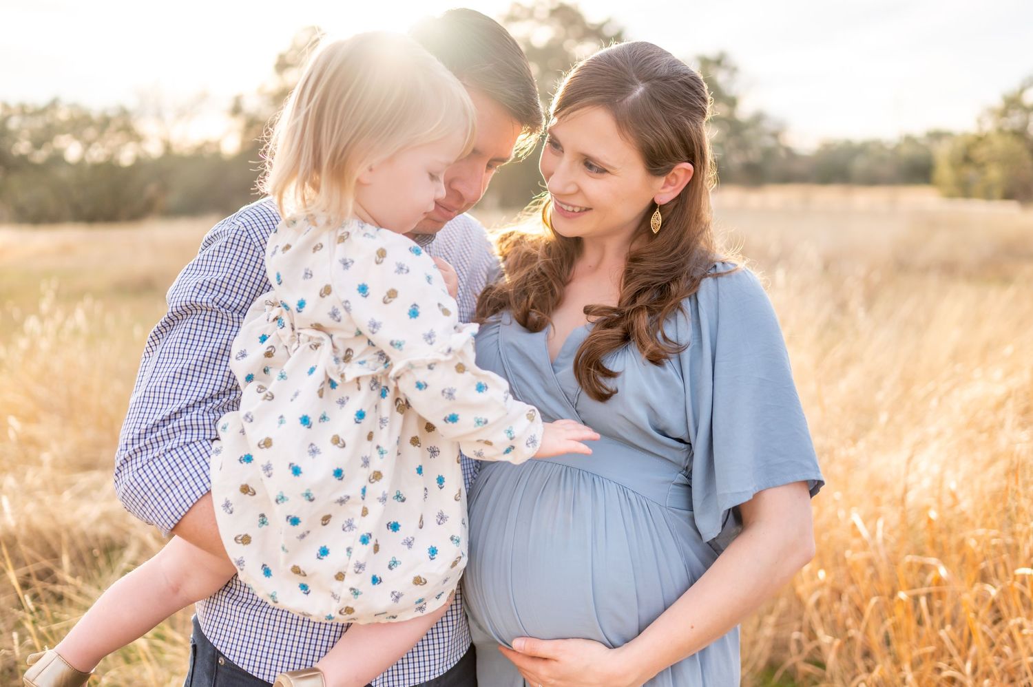 Intimate family moment in golden sunlit field.