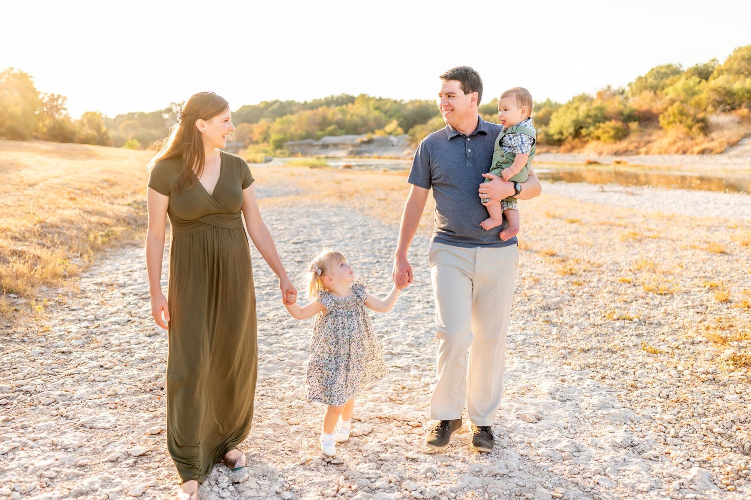 Family walking together on sandy path during sunset.