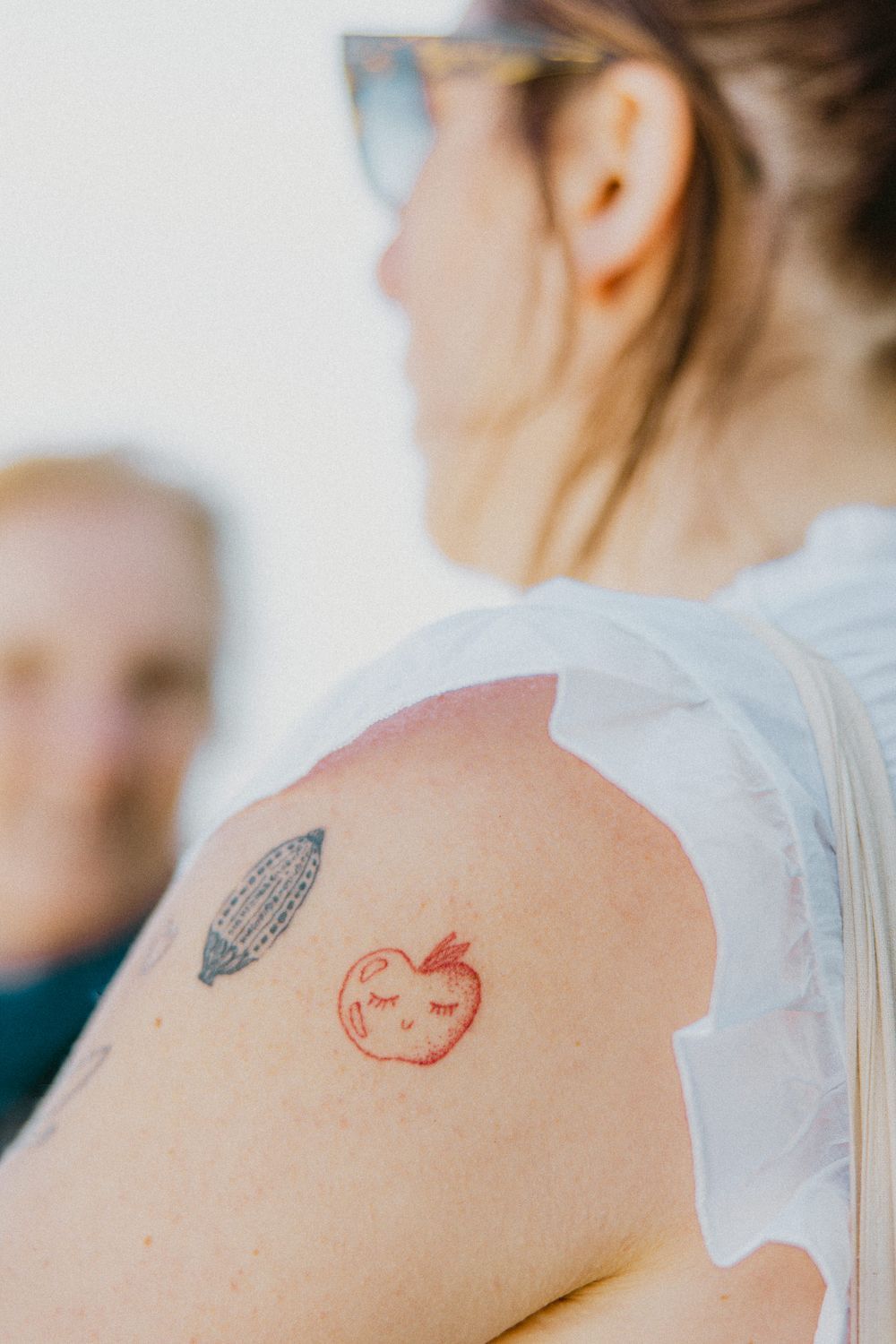 Close-up of minimalist apple tattoo design on shoulder.