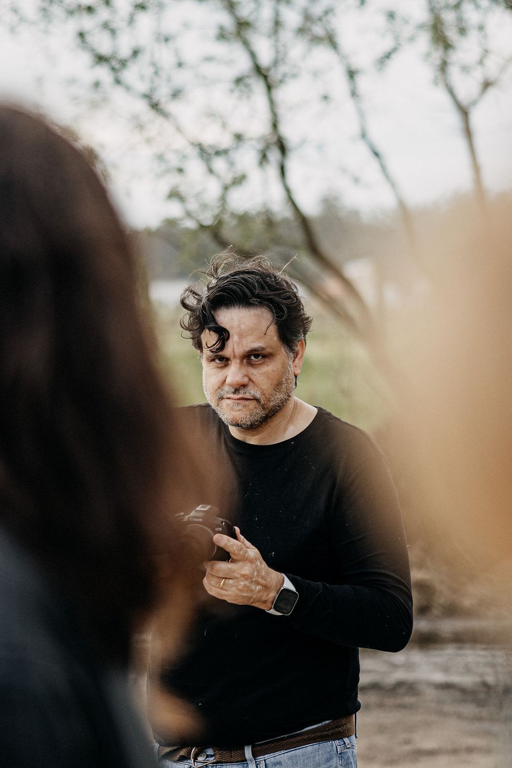 Person in black sweater holding something while standing outdoors.
